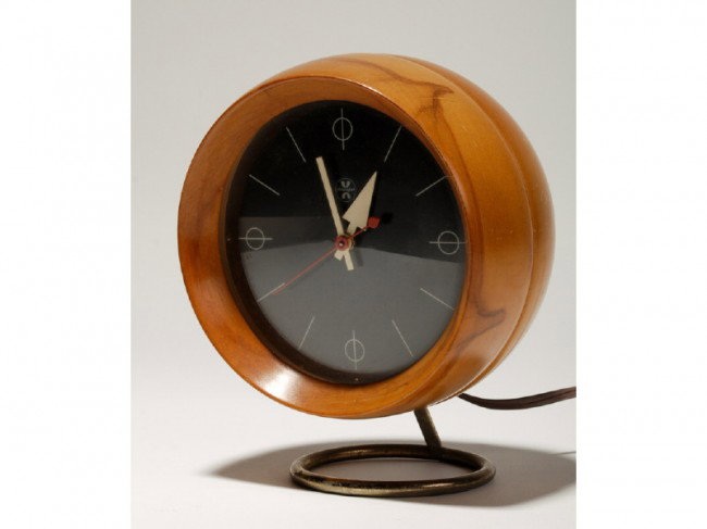 Howard Miller Mid Century Nelson Birch Clock: George Nelson round birch table clock raised on a circular brass plated metal base. The black dial is marked Chronopak. The clock is in good condition with light wear from normal use. Measures 7" high