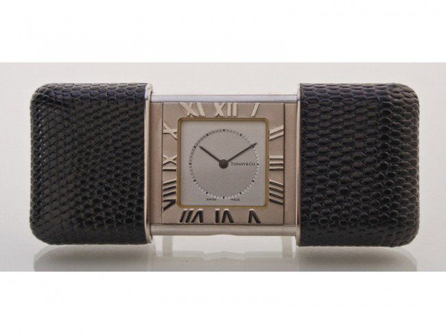Tiffany Stainless Travel Alarm Clock w Box &Papers: Tiffany stainless steel quartz travel alarm clock. The compact black leather covered travel clock is in good condition and includes the original box with pamphlets. The watch is running and keeping ac