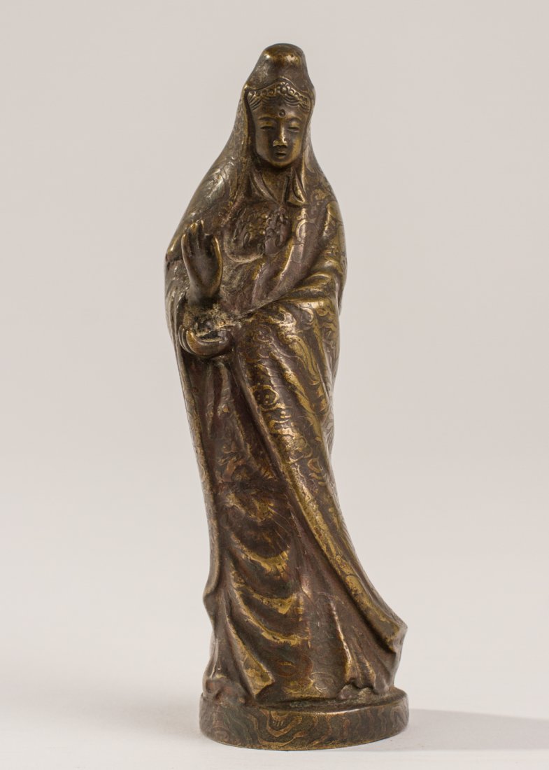 Chinese Bronze Buddhist Figure of Kwan Yin Mudra: Chinese Bronze Figure of Kwan Yin. Left hand raised in Buddhist mudra meditation. The gown the figure is wearing has embossed all over floral decoration. In good condition. Measures 6 inches in height