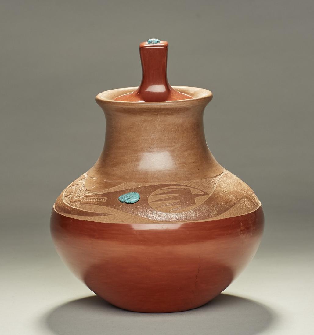 San Ildefonso signd Russell Sanchez Turquoise Jar: Native American Indian San Ildefonso Russell Sanchez turquoise Jar. The two color pottery covered jar is set with a turquoise on the body and one on the top of the handle of the lid. There is a serpen