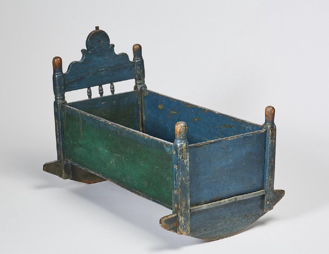 Old Green Painted 19th Century Childs Cradle: Old Green Painted 19C Childs Cradle. The early 19th century cradle has a shaped headboard with turned spindles. The corners have elongated knob tops. In good condition with wear from normal use measur