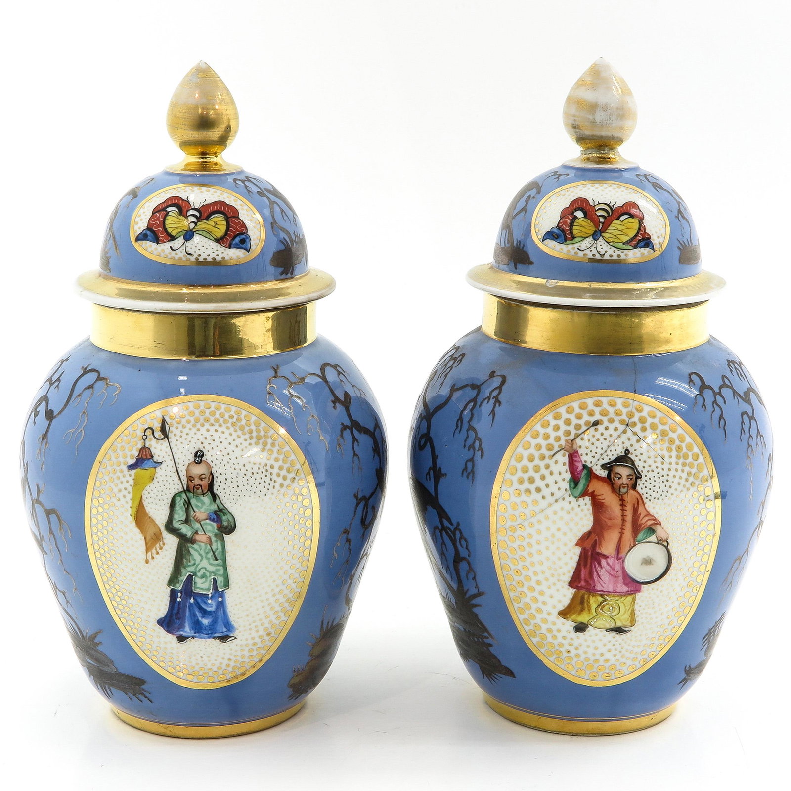 A Pair of Vases with Covers: Polychrome decor of Chinese figures with gilt accents, 29 cm. tall, in diverse conditions.