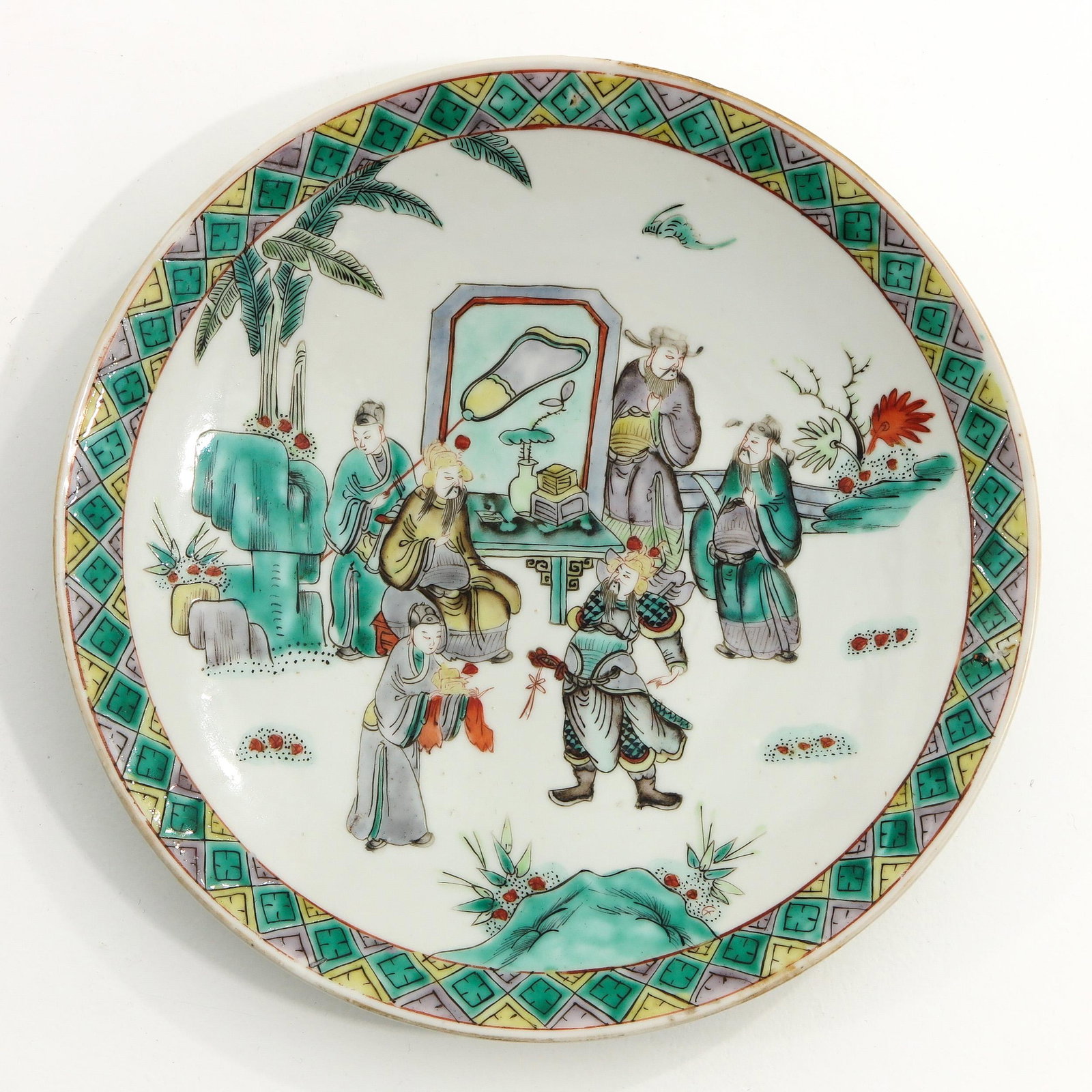 A Famille Verte Plate: Depicting Chinese figures in garden, 20 cm. in diameter, chip.