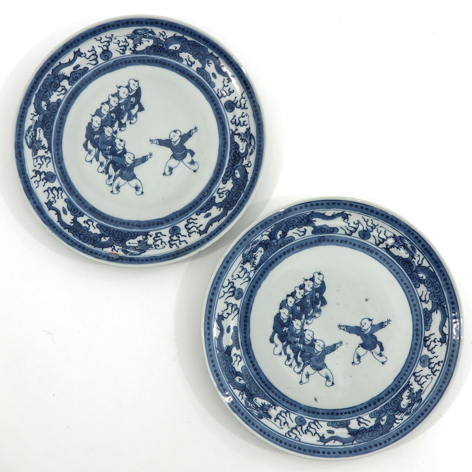 A Pair of Blue and White Plates: Depicting Chinese children in center of plate with dragons on border, 24 cm. in diameter.