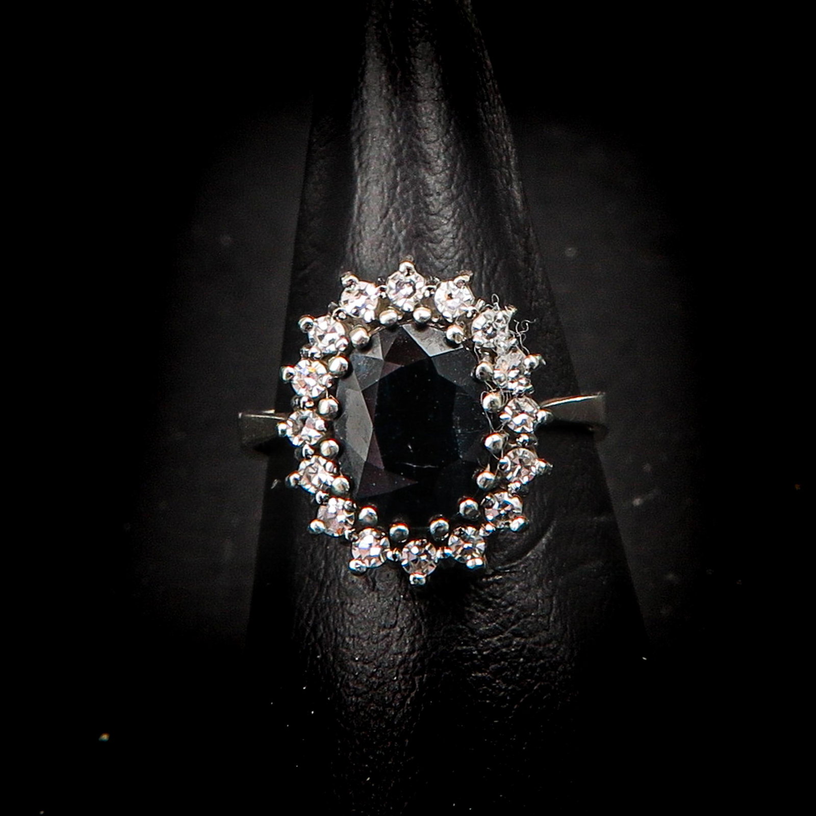 A 14KG Diamond and Sapphire Ring: Set with 16 brilliant cut diamonds and 1 sapphire, approximately 6 x 9 mm., ring size 17.