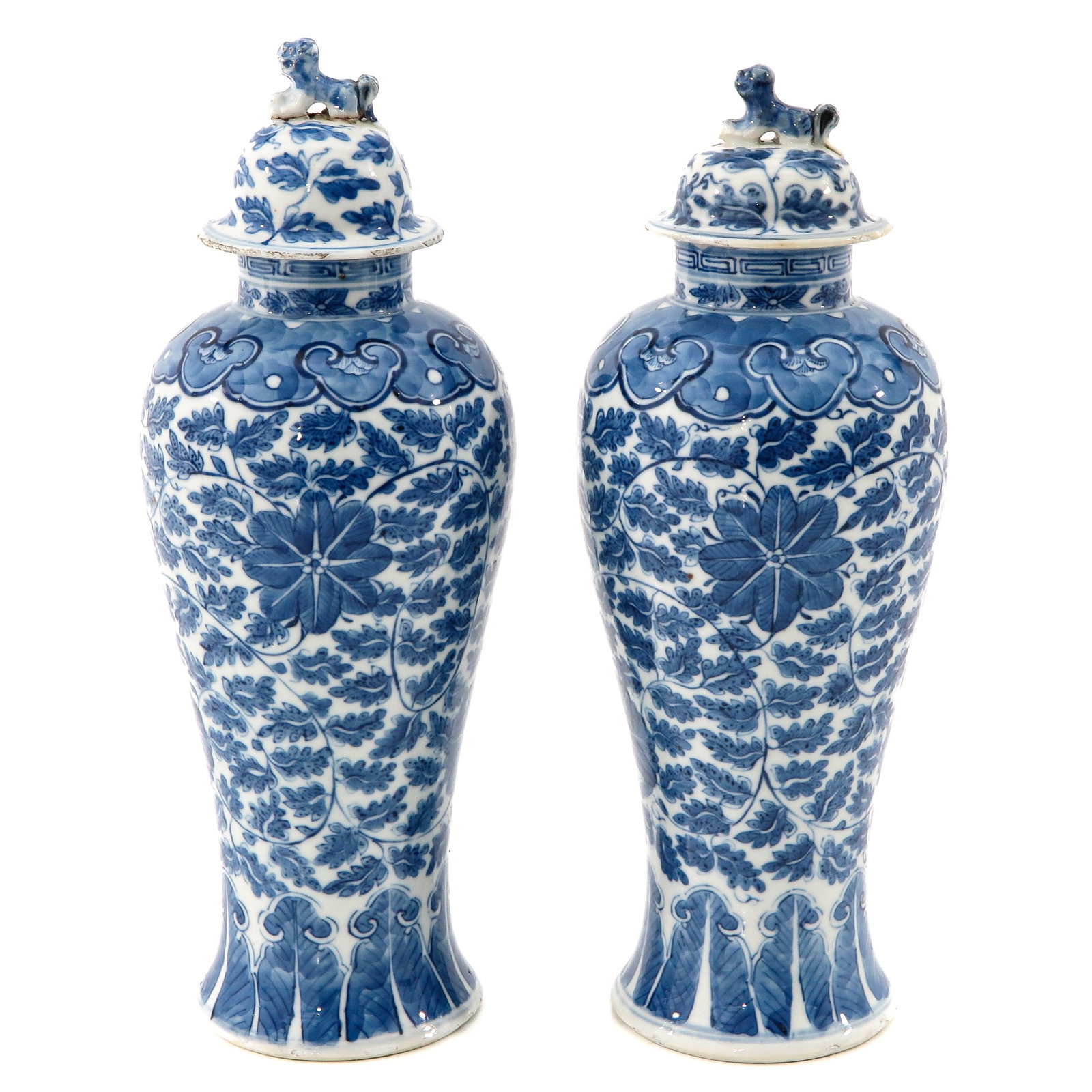A Pair of Blue and White Vases with Covers: Floral decor, 28 cm. tall, temple lions on covers, one cover with restoration.