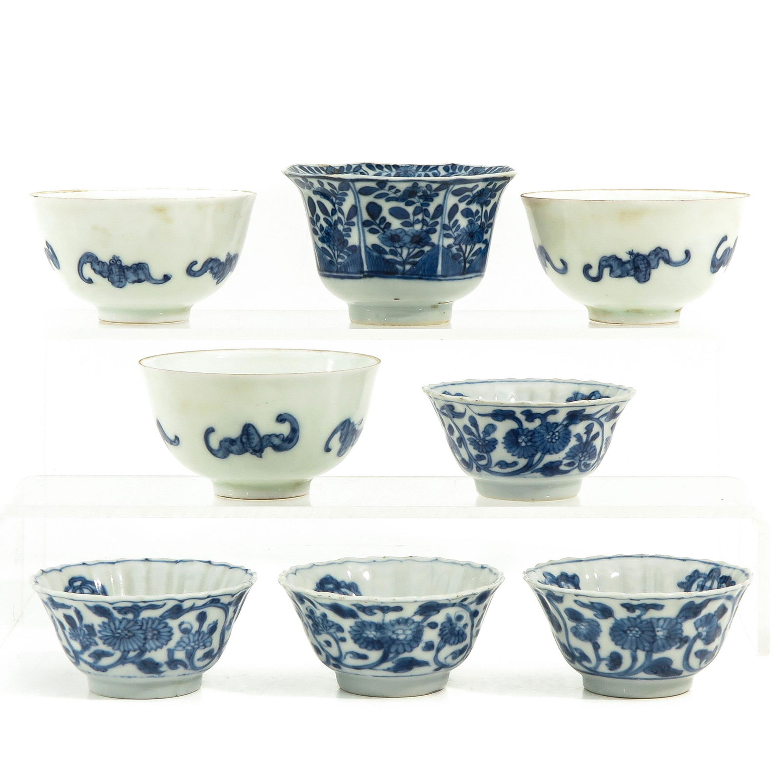 A Collection of 8 Blue and White Cups: In a variety of decors and sizes, largest cup is 8 cm. in diameter.