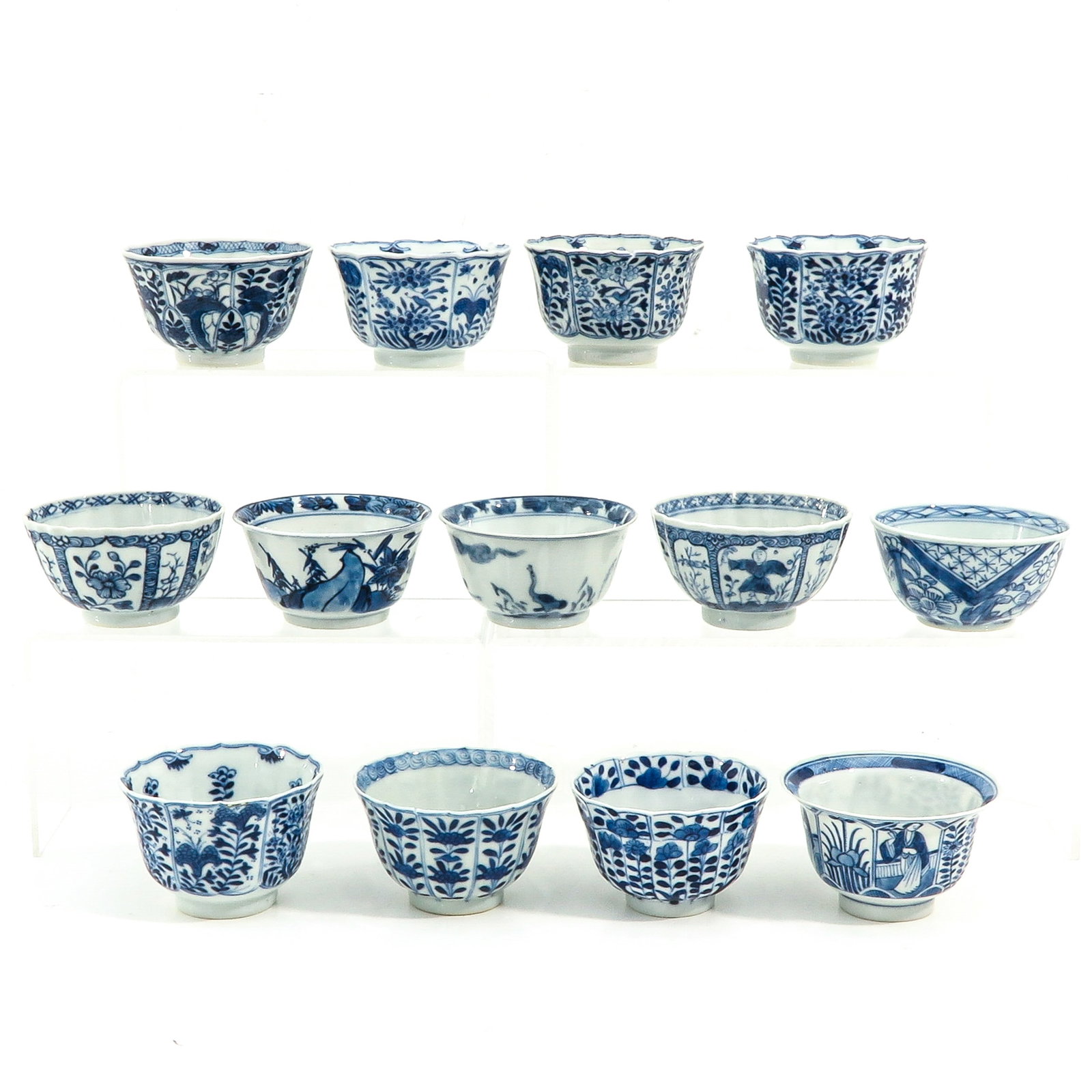 A Collection of 13 Blue and White Cups: In a variety of decors and sizes, including 18th Century, largest cup is 9 cm. in diameter, chip and hairline.