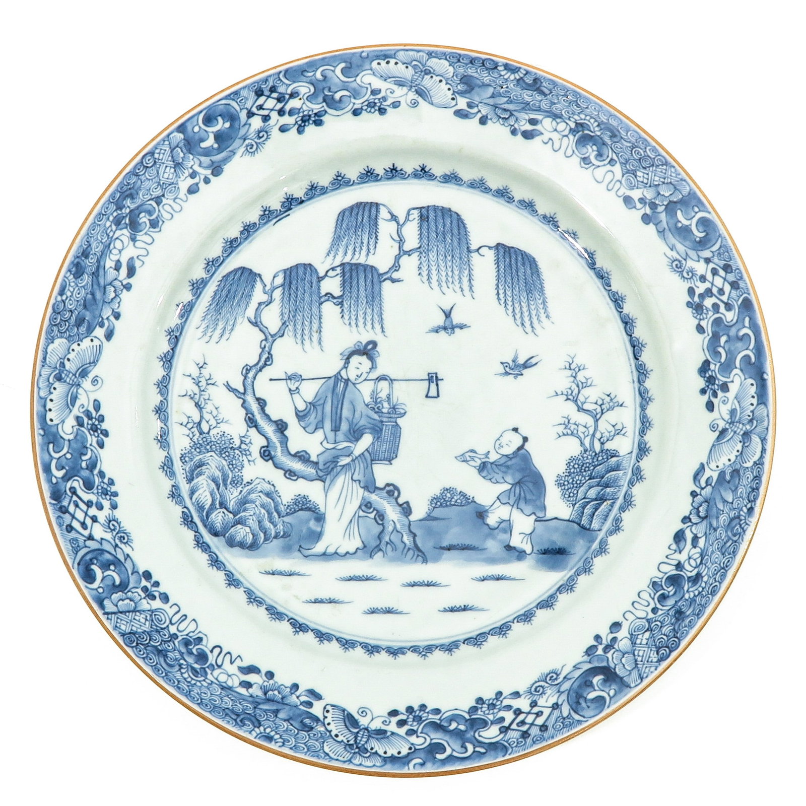 A Blue and White Charger: Center of charger depicting lady carrying basket in garden with boy offering fish as a gift, border decorated with flowers and buterflies, 18th Century, 31 cm. in diameter.