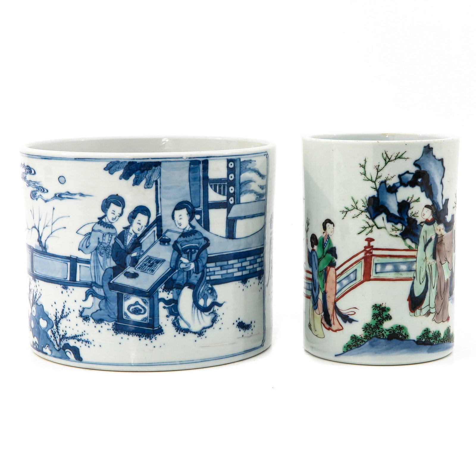 A Famille Verte and Blue and White Brush Pot: Famille Verte brush pot decorated with various figures on terrace. The Blue and White brush pot is painted with figures playing games. Both brush pots are 15 cm. tall.