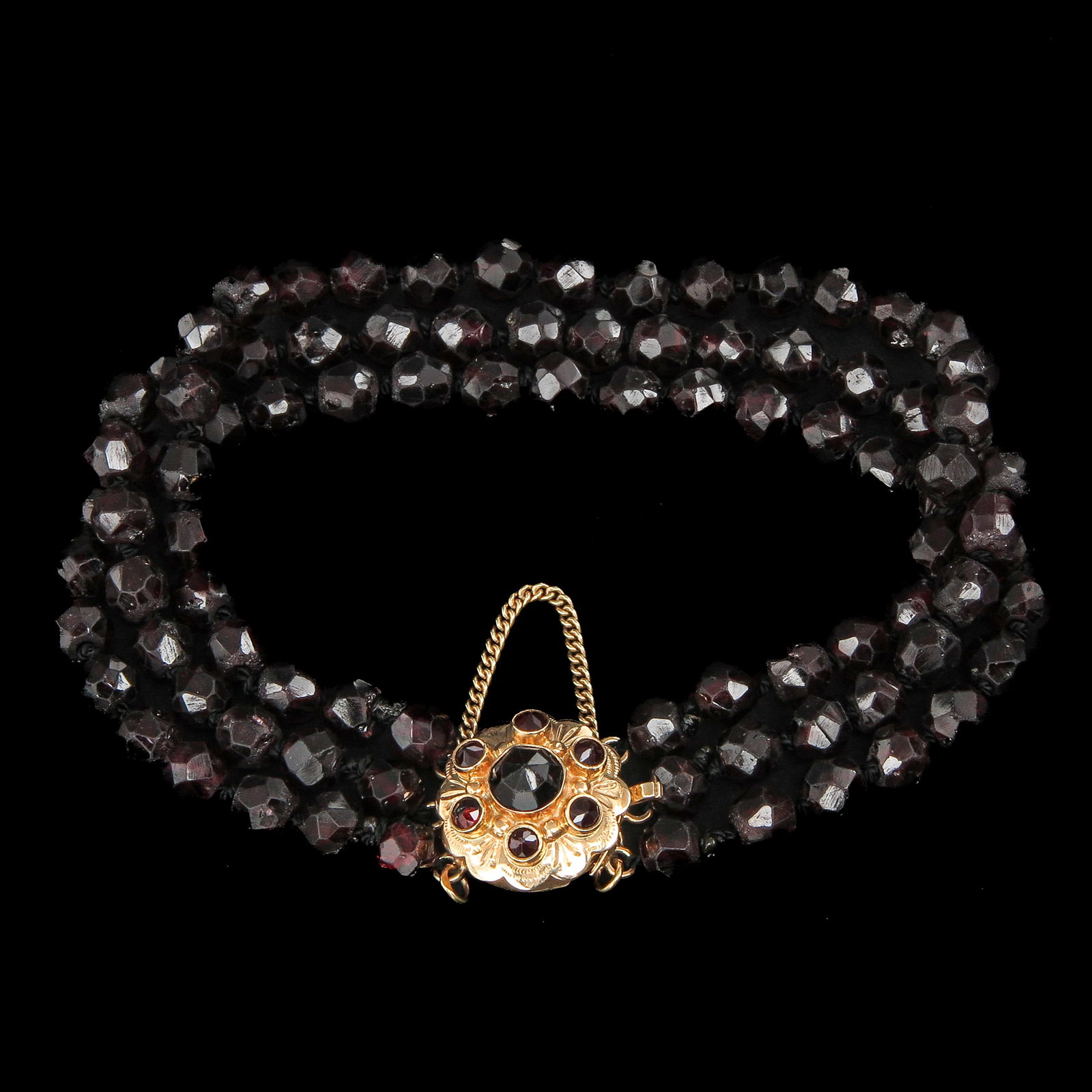 A Bracelet: with 3 rows of garnet, on 14 carat gold clasp