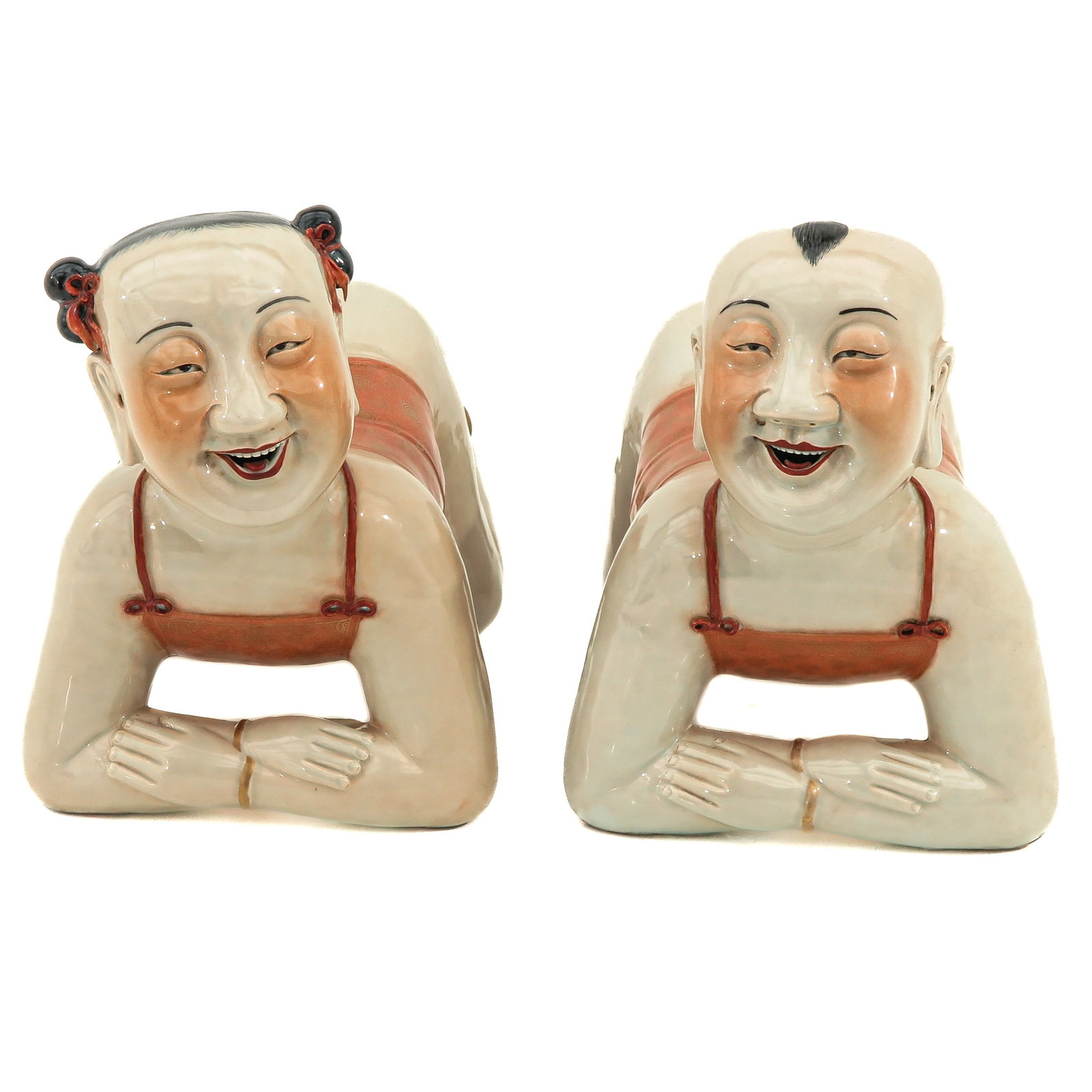 A Pair of Porcelain Pillows: Depicting a Chinese girl and boy resting on their knees and elbows, 40 cm. long.