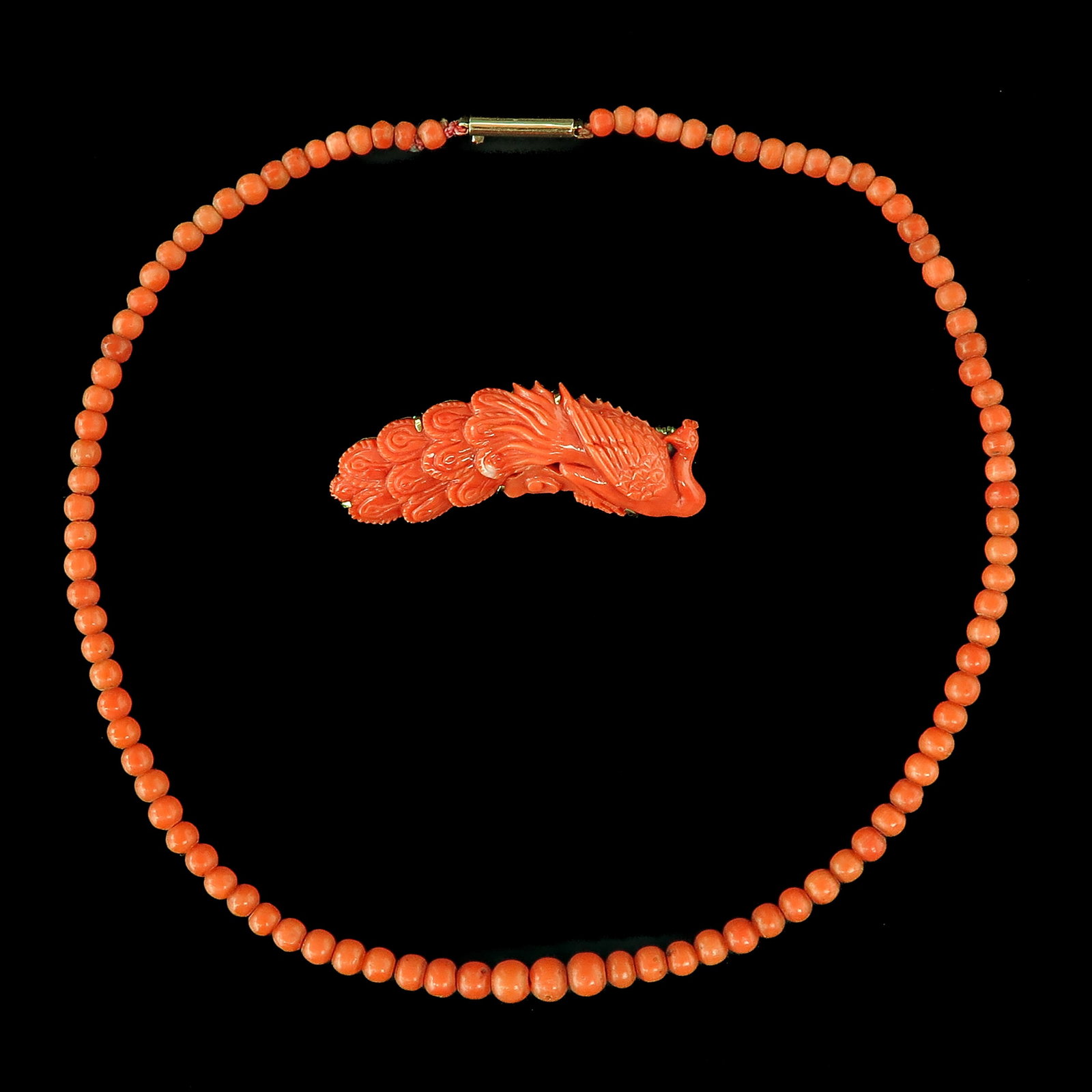 A Red Coral Necklace and Brooch: consisting of necklace and brooch in the shape of a peacock, with 14KG mountings, length 44 mm.