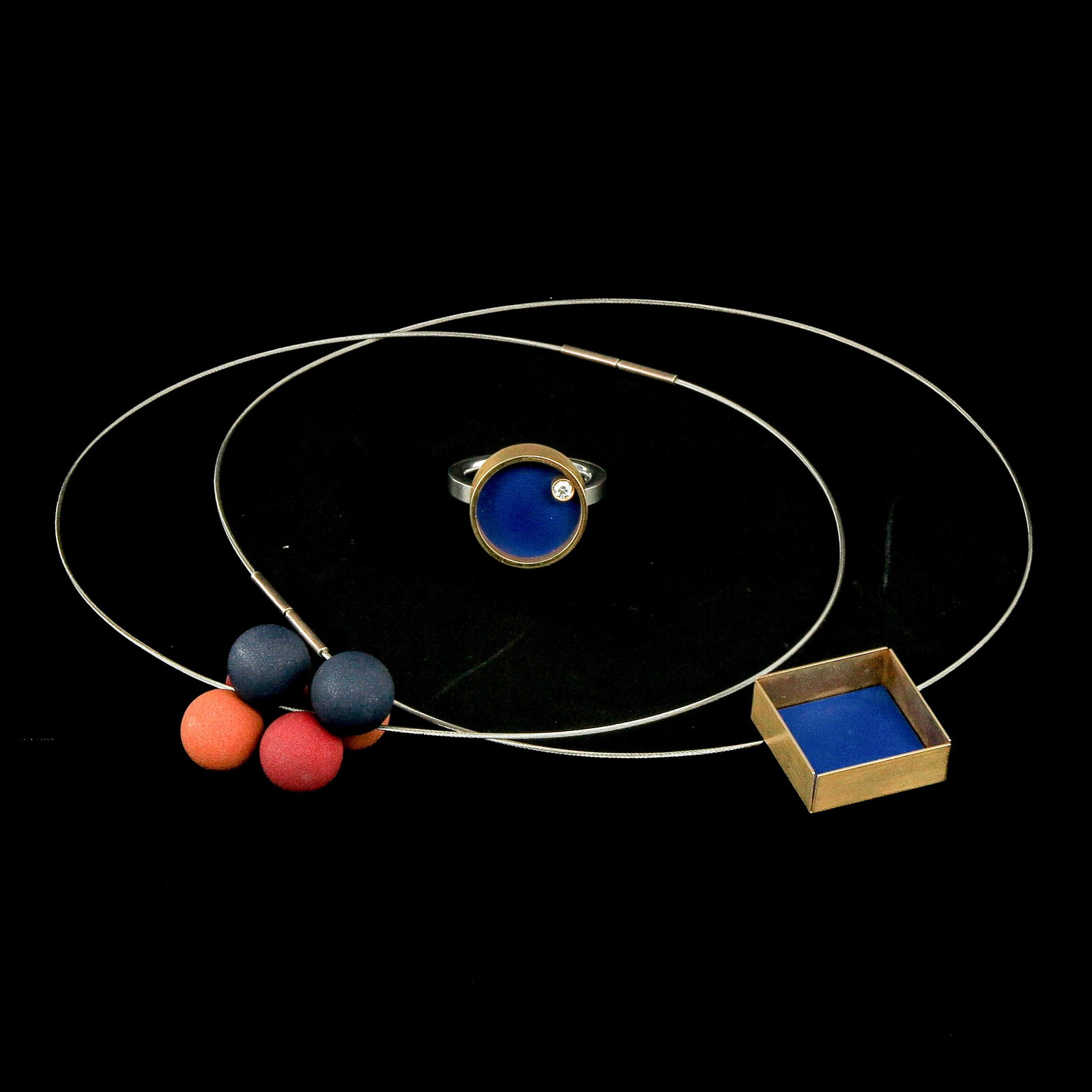 A Group of Jewelry from Designer Carl Dau: consisting of two necklaces by German designer Carl Dau. One necklace with a square blue pendant and the other with colourful geometric elements in red, orange and blue, incl. 18KG on steel ring with 