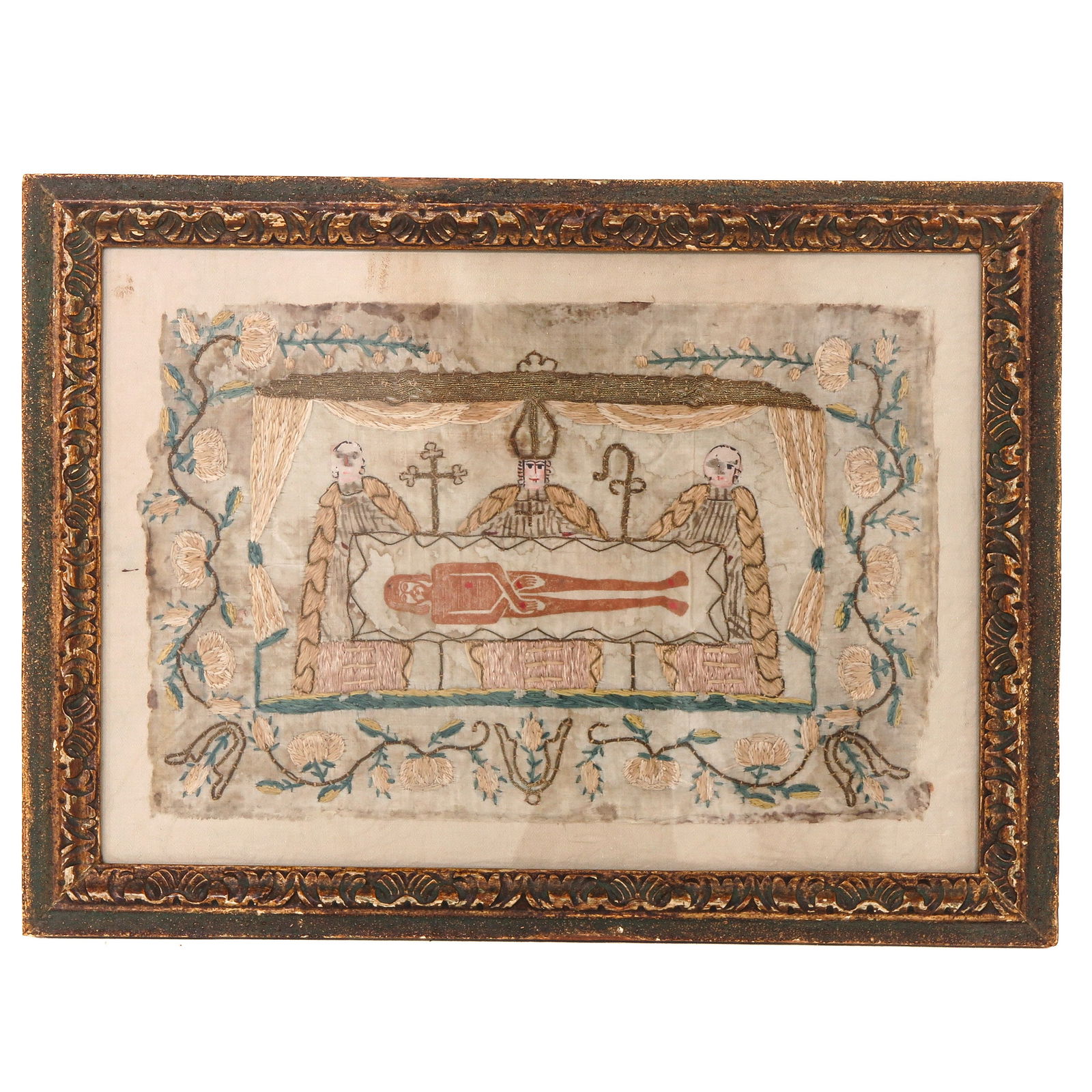 A Religious Frame: with embroidered religious scene on silk, depicting Christ in the tomb, surrounded by instruments of the passion, 46 x 34 cm.