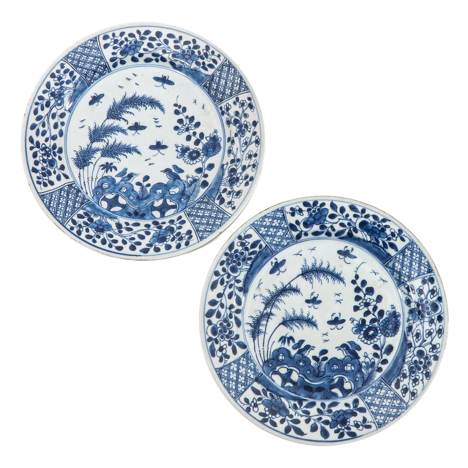 A Pair of Blue and White Plates: Depicting a scene in a garden with flowers, birds, and rocks, 18th Century, 28 cm. in diameter, chip