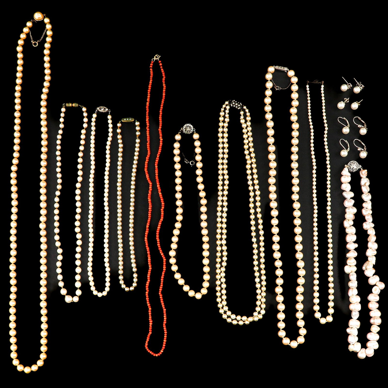 A Diverse Group of Jewelry: Various necklaces and earrings, including red coral.