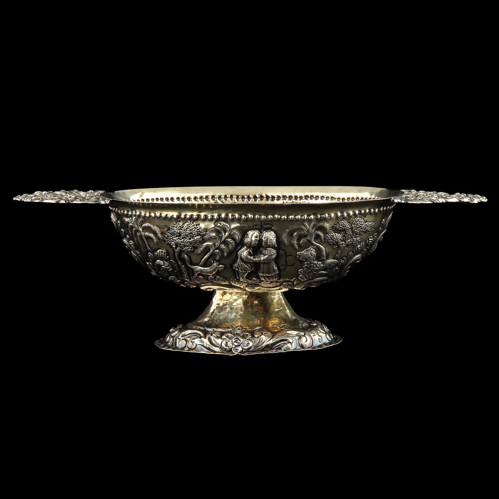 A Silver Brandy Bowl: Silver, oval, decorated with figures in a garden, length 26 cm.