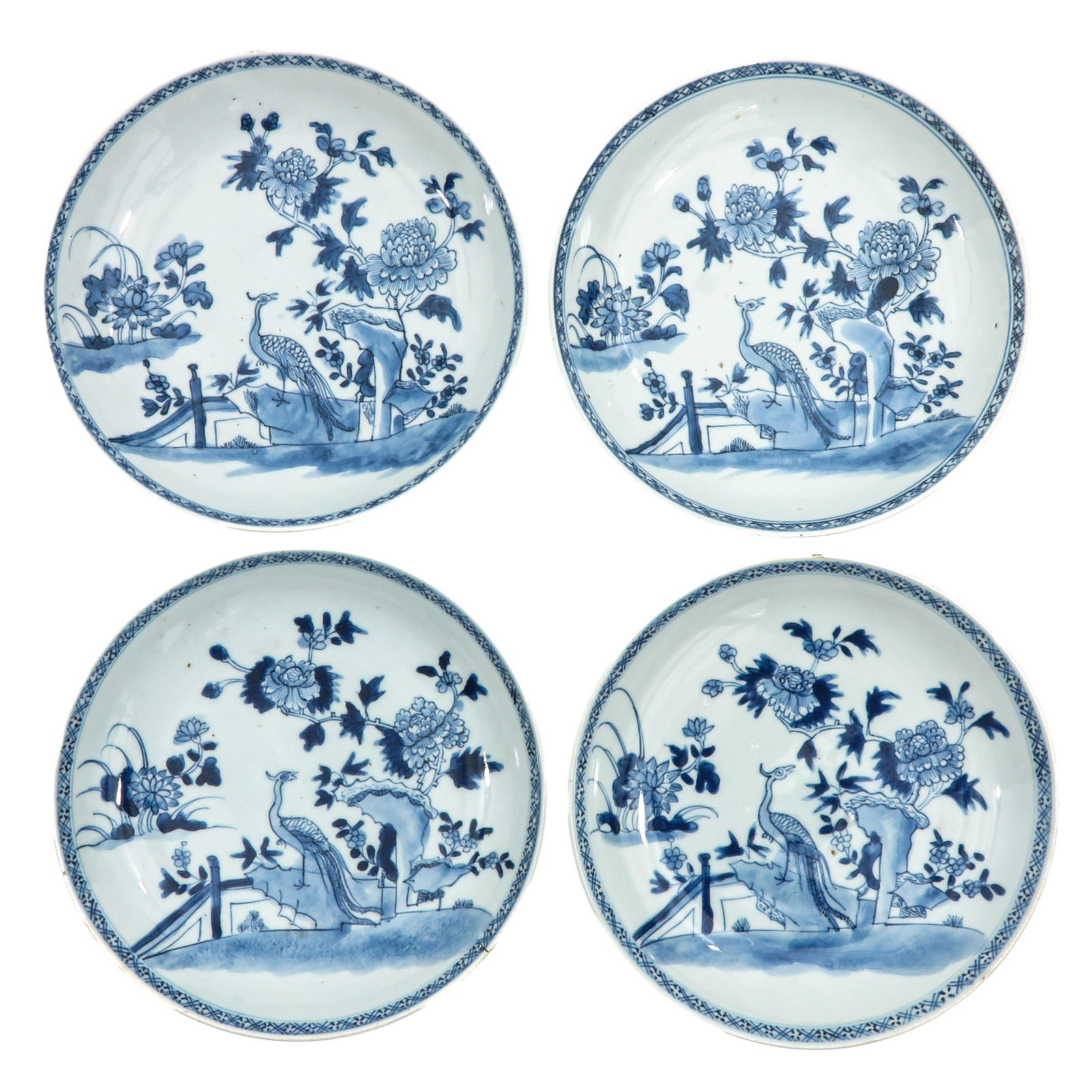 A Series of 4 Blue and White Plates: Each decorated with a peacock in a garden setting among flowering peonies, and a low fence, 18th Century, 22 cm. in diameter, chip.