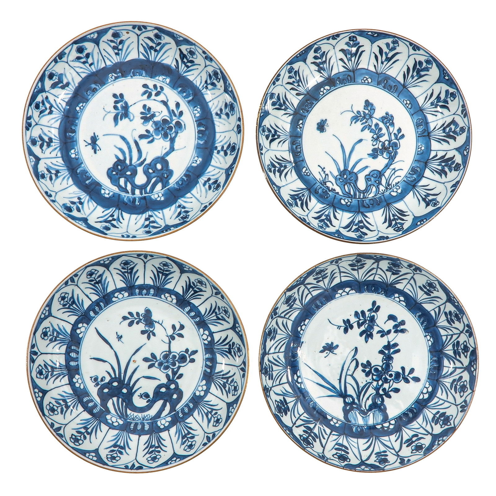 A Set of 4 Blue and White Plates: Each painted to the center with flowering plants and rockwork, 18th Century, 22 cm. in diameter, hairline.