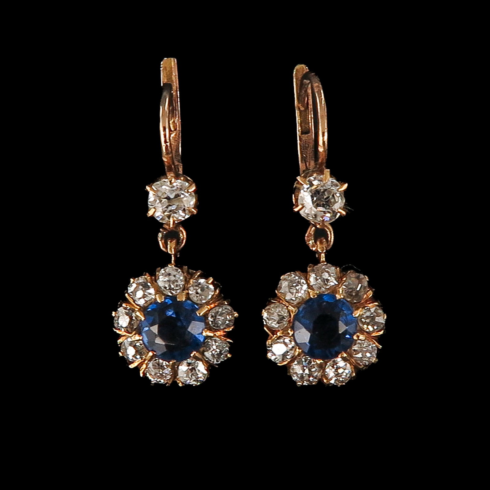 A Pair of 14KG Diamond and Sapphire Earrings: 14 Krt. gold, each set with a sapphire, surrounded by 9 antique-cut diamonds and one above, length 22 mm