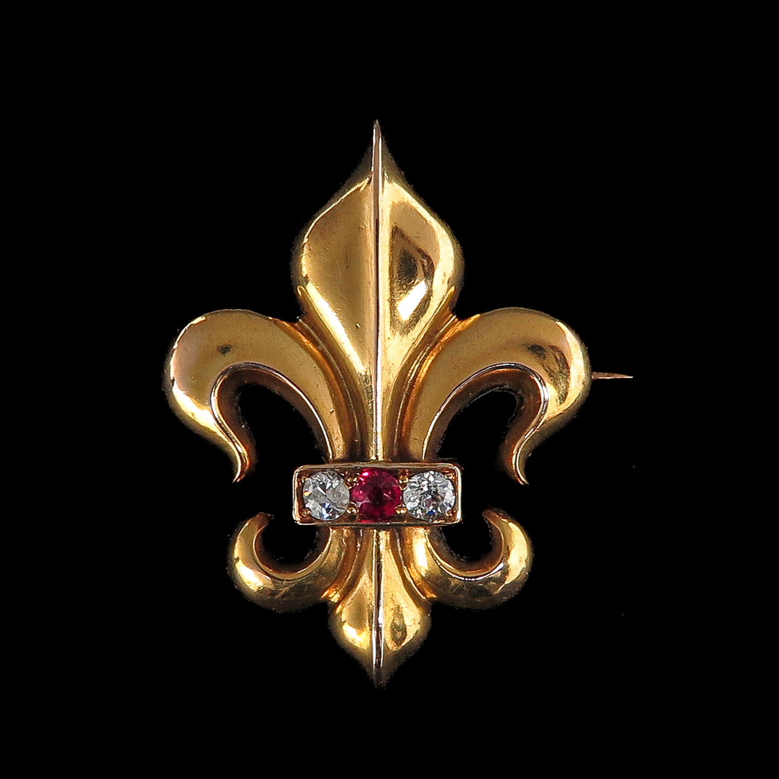 A 14KG Diamond and Ruby Brooch: 14 Krt. gold, in the shape of a French lily (fleur-de-lis), set with a central antique cut ruby ??and 2 antique cut diamonds, 27 x 37 mm