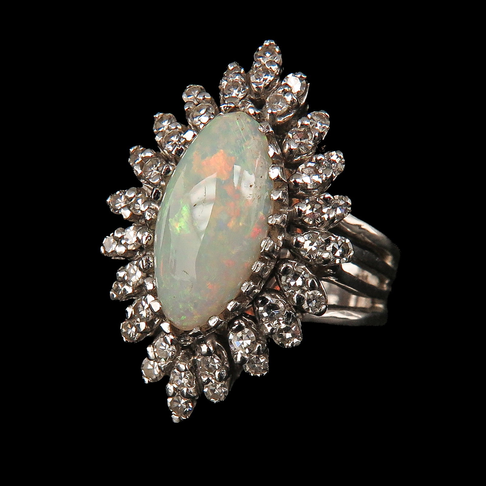 A Ladies Opal Ring: 14 Krt. gold, set with a marquise-cut opal in the center, surrounded by many diamonds, ring size 17.5