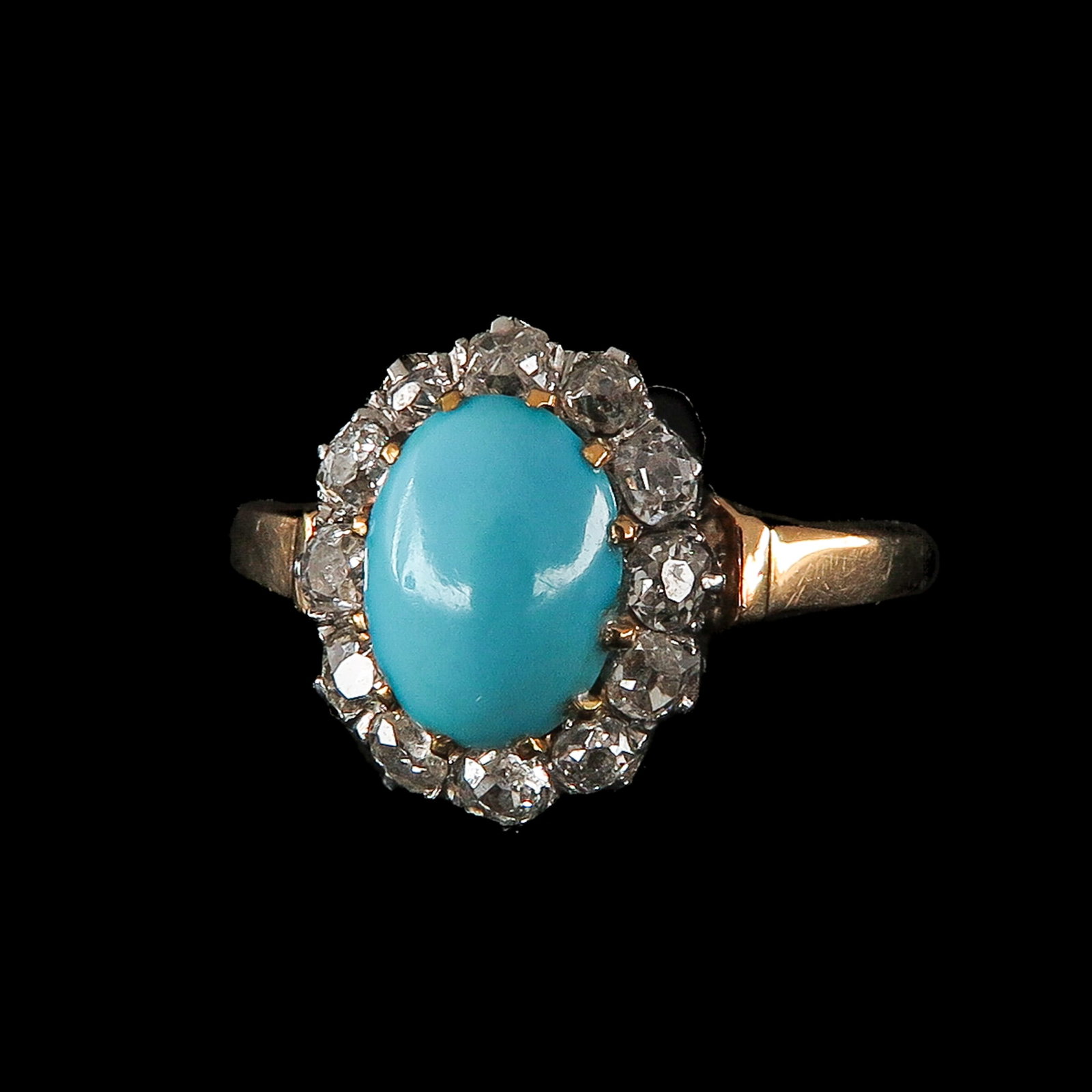 A Ladies Turquoise and Diamond Ring: 18 Krt. gold, set with an oval-cut turquoise, surrounded by 12 diamonds, ring size 17.5