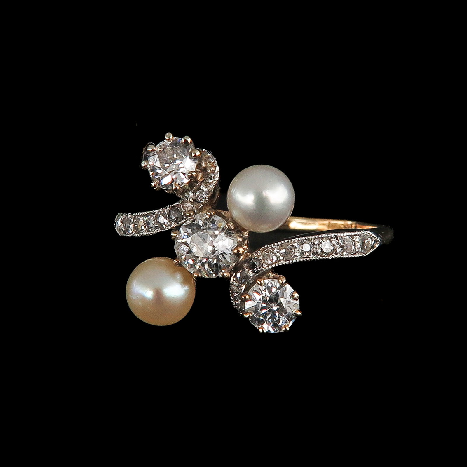 A Ladies Diamond and Pearl Ring: 18 Krt. gold, Art Nouveau, set with 3 diamonds and 2 pearls, the shank is set with 16 small diamonds in platinum, ring size 18