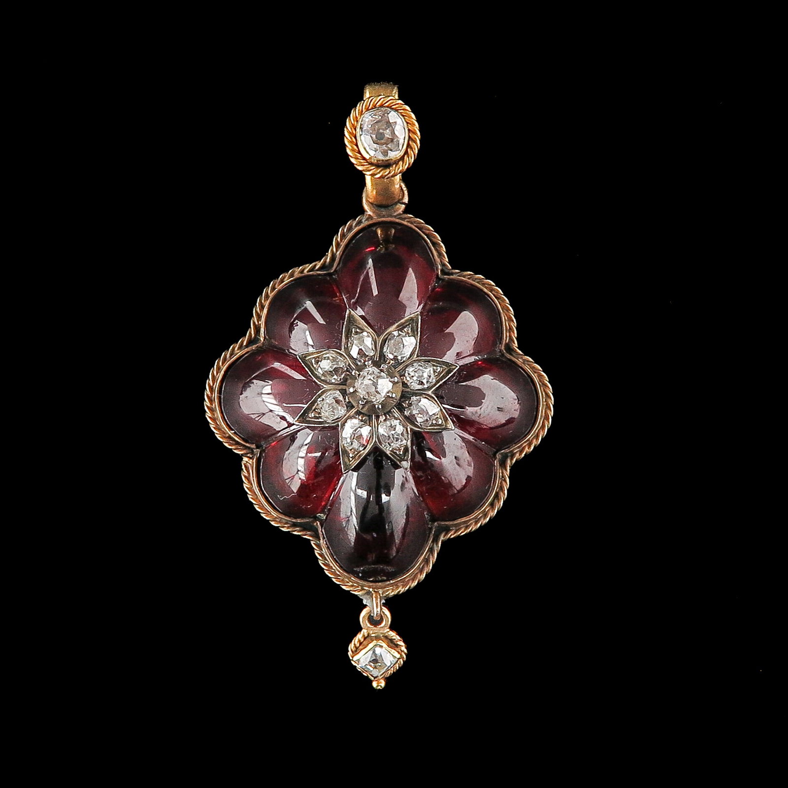 A Garnet and Diamond Pendant: 14 Krt. gold, set with 8 cabochon-cut garnets, the heart with a silver appliqué set with diamonds, the back with hair compartment, length 50 mm