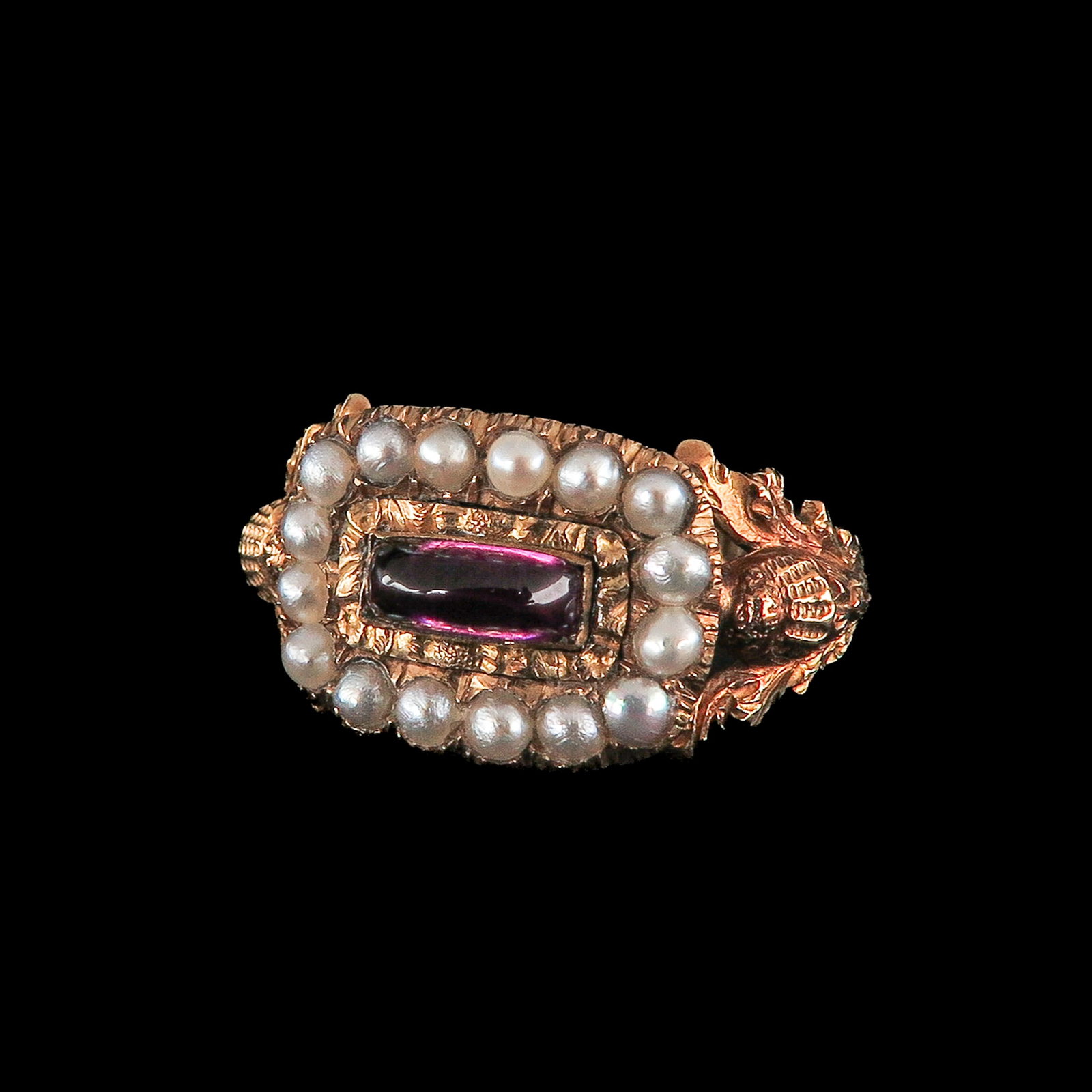A Ladies 18KG Garnet and Pearl Ring: 18 Krt. gold, England, 1827, set with a rectangular almandine garnet, surrounded by a rim of half pearls, ring size 17