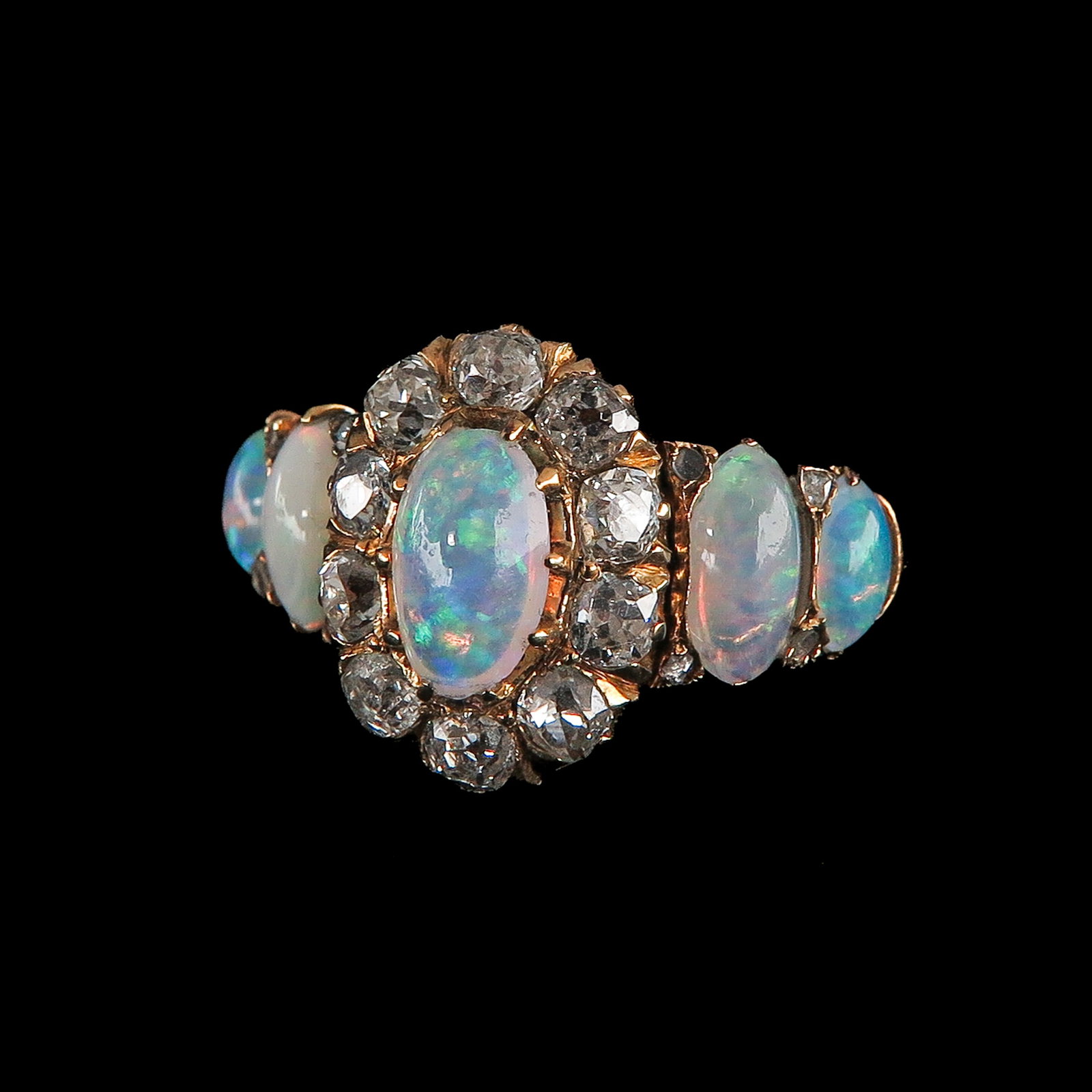 A Ladies Opal and Diamond Ring: 14 kt. gold, set with an oval-cut opal, surrounded by 10 diamonds, on either side 2 oval-cut opals, ring size 17.5