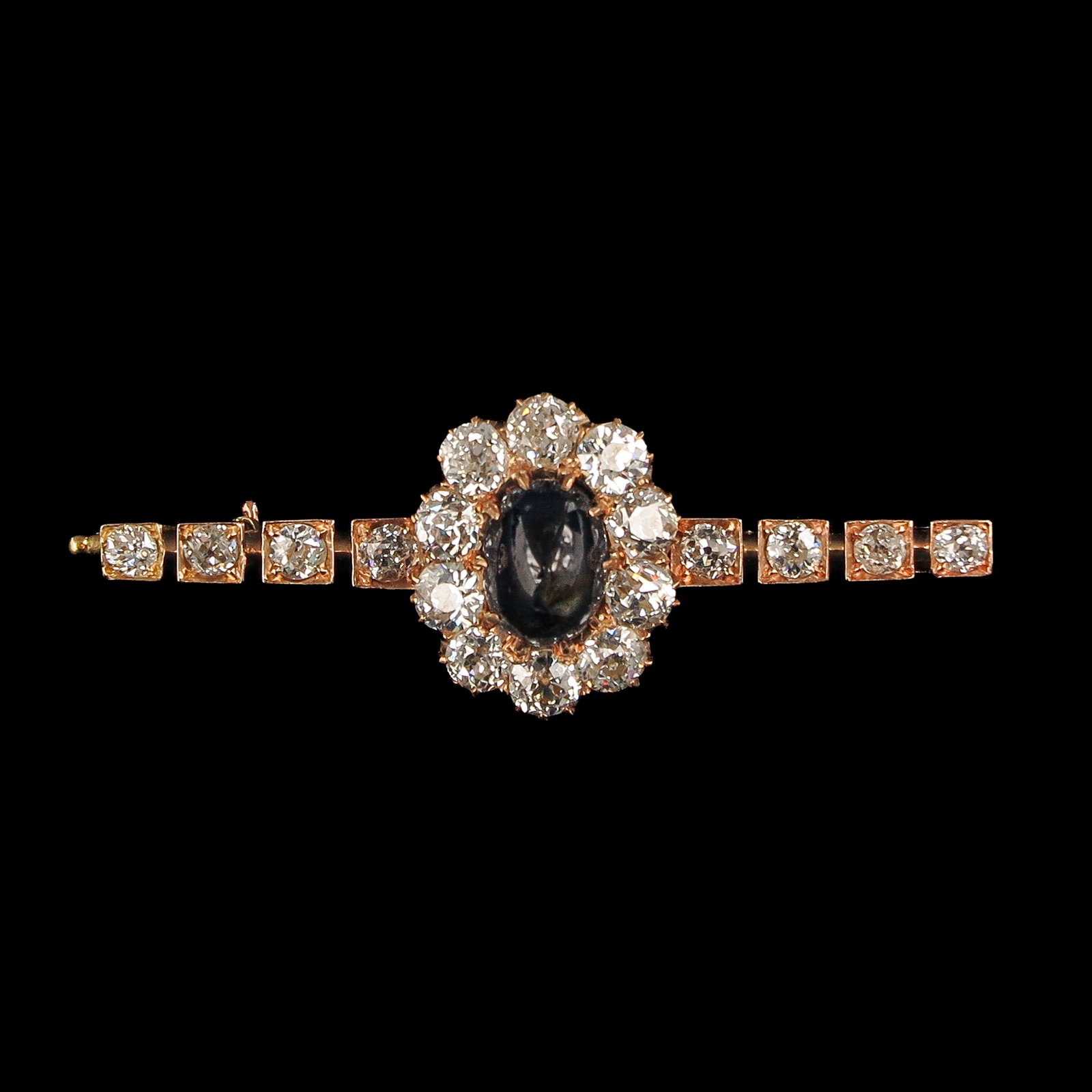 A Sapphire and Diamond Brooch: 14 Krt. gold, possibly Russian, set with a blue cabochon-cut sapphire, surrounded by 10 Bolshevik-cut diamonds, the sides set with another 8 Bolshevik-cut diamonds, total weight 2.6 ct., length 47 mm