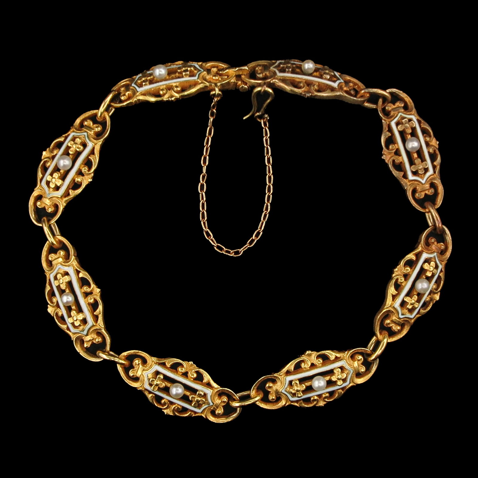 An 18KG Bracelet: 18 Krt. gold, France, ca. 1900, consisting of 8 openwork links, each set with a seed pearl and surrounded by small borders with white enamel, length 17 cm