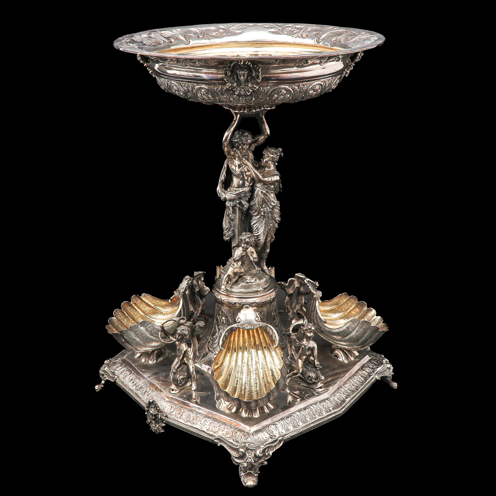 A Fine Silver Centerpiece by Lale Silverware Co.: from Lale Silverware Co., Ltd., marked Lale 925 sterling, the bowl with high-relief foliage, floral heads and fluting, with gilded interior and gilded shells, on a column with classical figures and a 