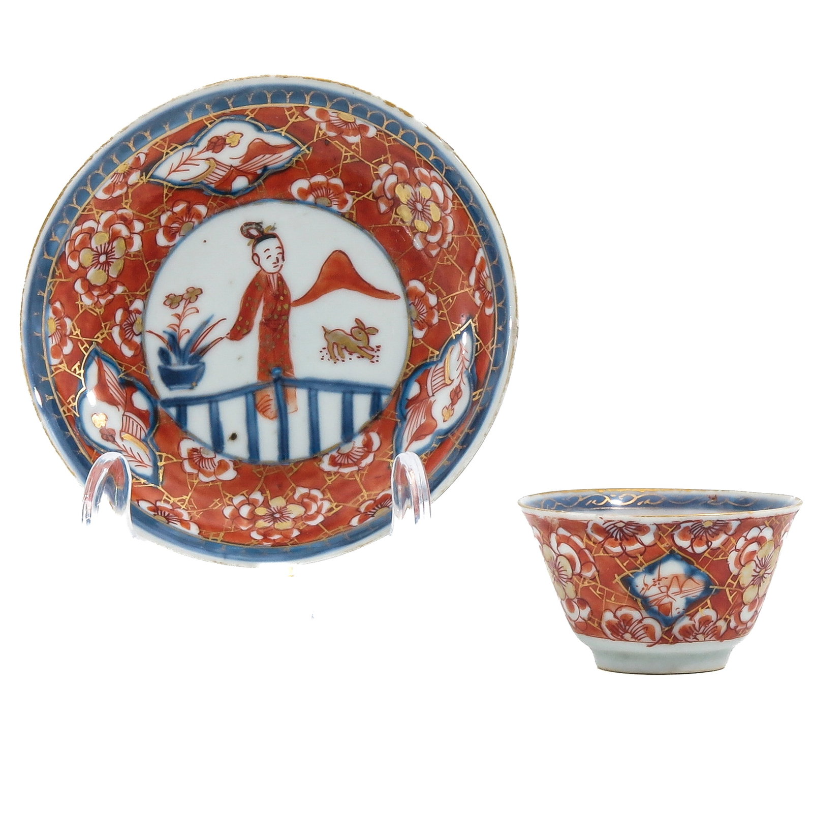A Cup and Saucer: Decorated with iron-red, underglaze blue and gilt, depicting a garden landscape with figures, Kangxi Period, 11 cm in diameter, chip and hairline.
