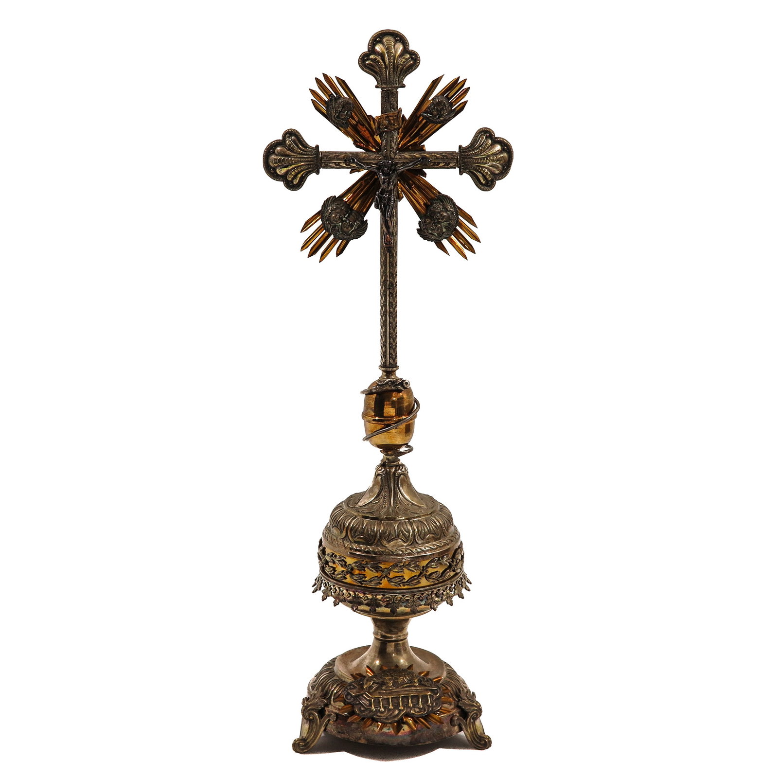 Standing Crucifix: finely crafted in silver-plated and gilded metal, the corpus placed in front of a halo with cherub heads, on an ornamented stem with a sphere and richly decorated base with the Lamb of God, height 71