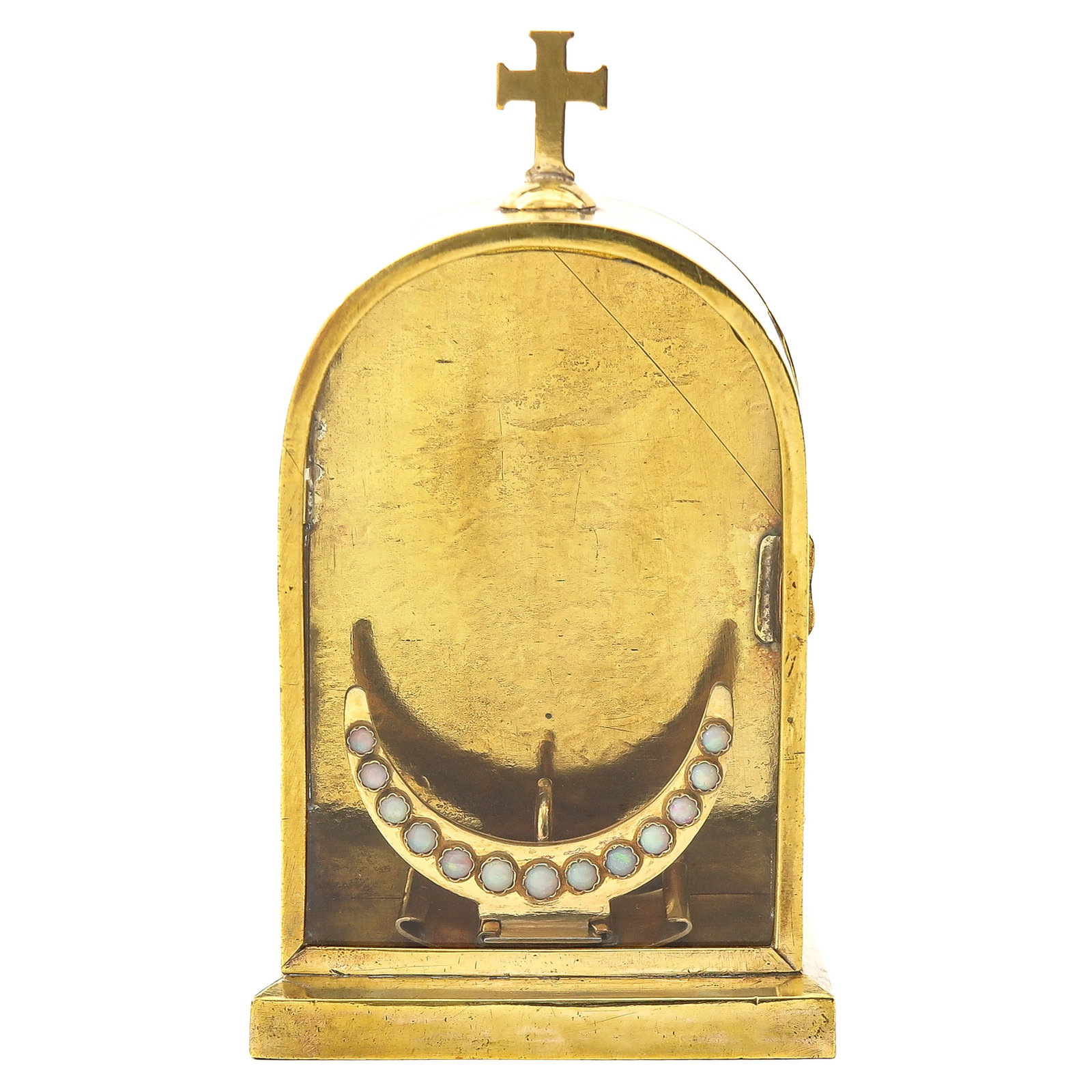 A Luna holder: of brass in the shape of a small tabernacle, crowned with a cross, interior fitted with a crescent-shaped holder set with stones, height 16 cm.