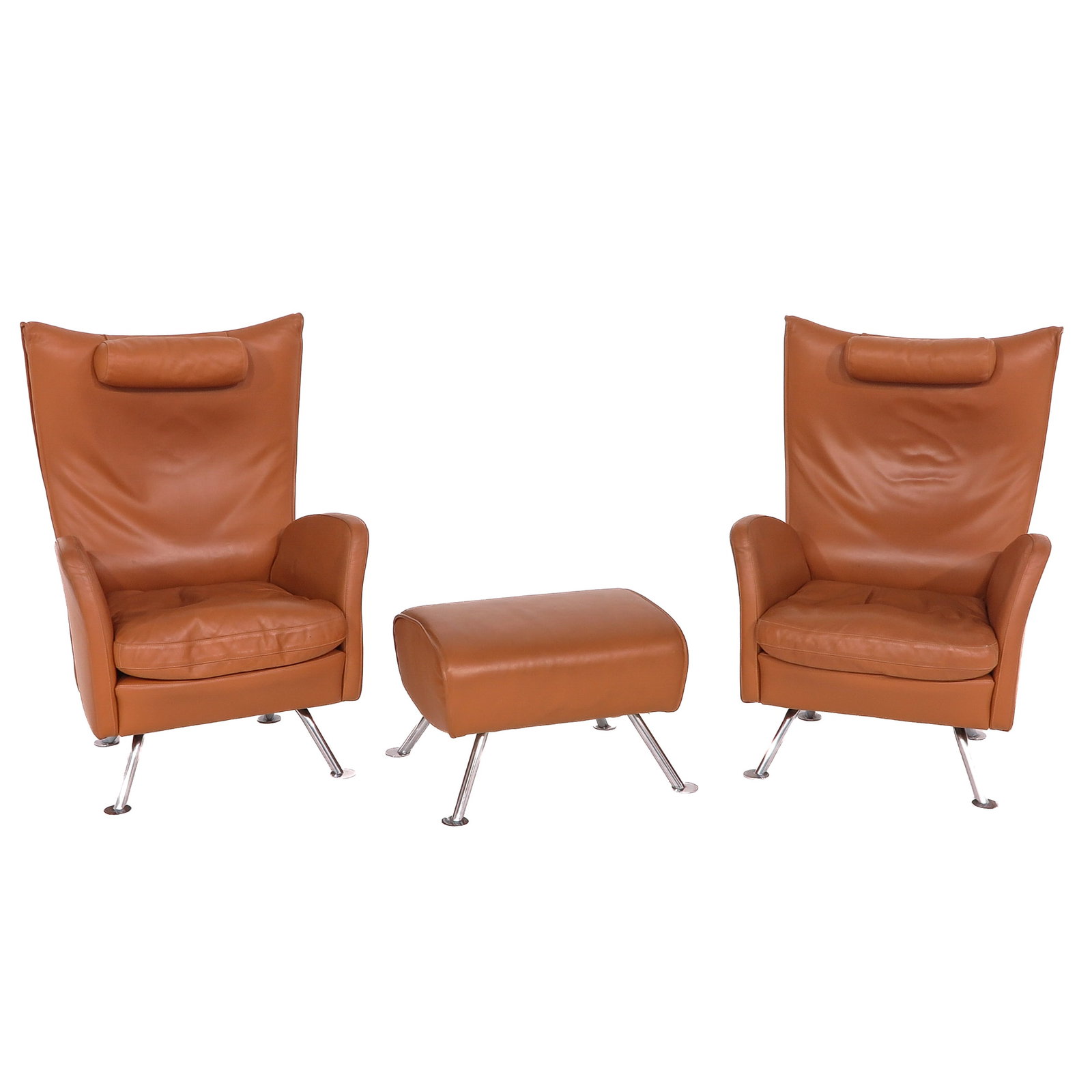 A Set of Armchairs: with matching ottoman, executed in cognac-coloured leather with metal legs, height 101 cm.