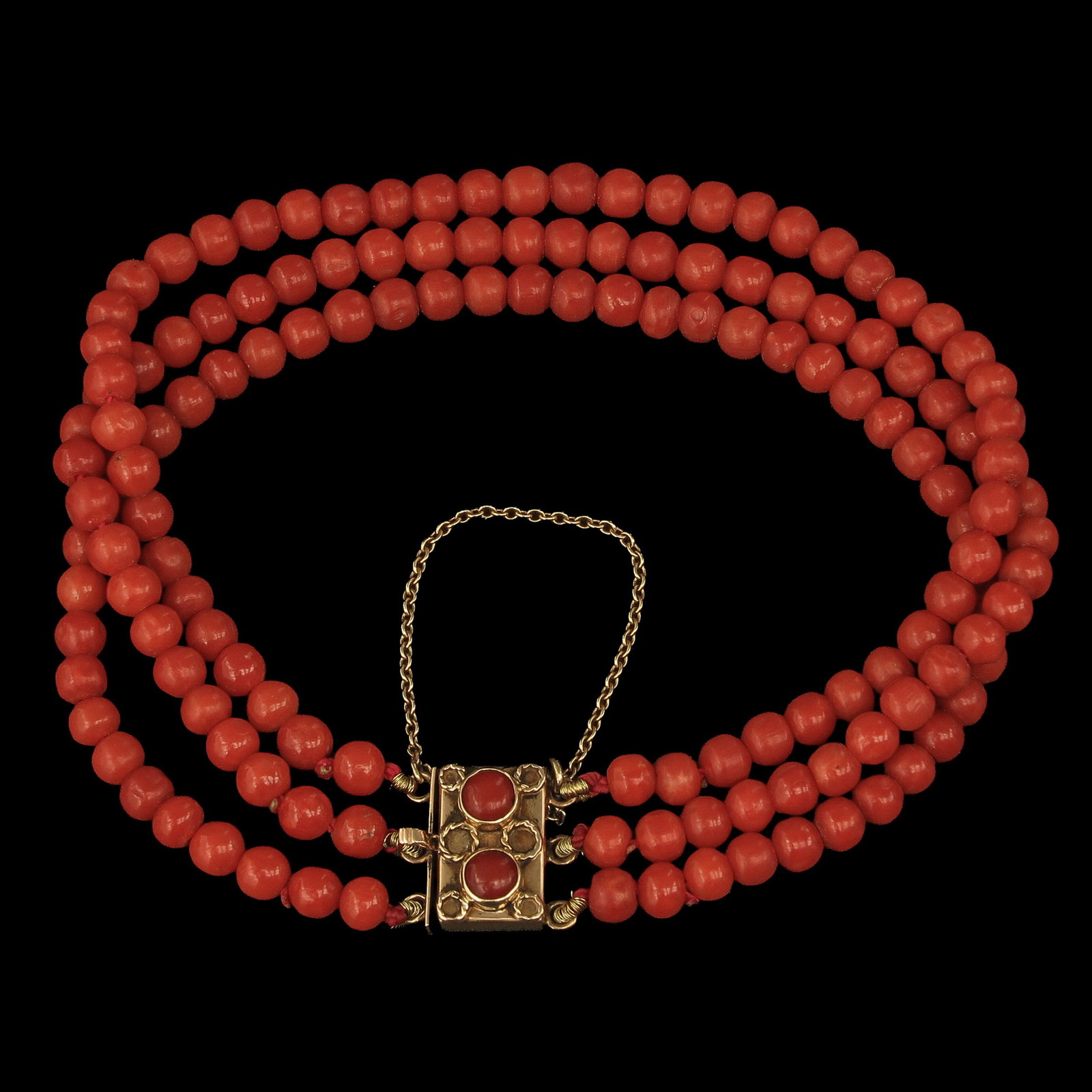 A Red Coral Bracelet: 3 rows red coral, 14 Krt. gold clasp, length 19 cm.