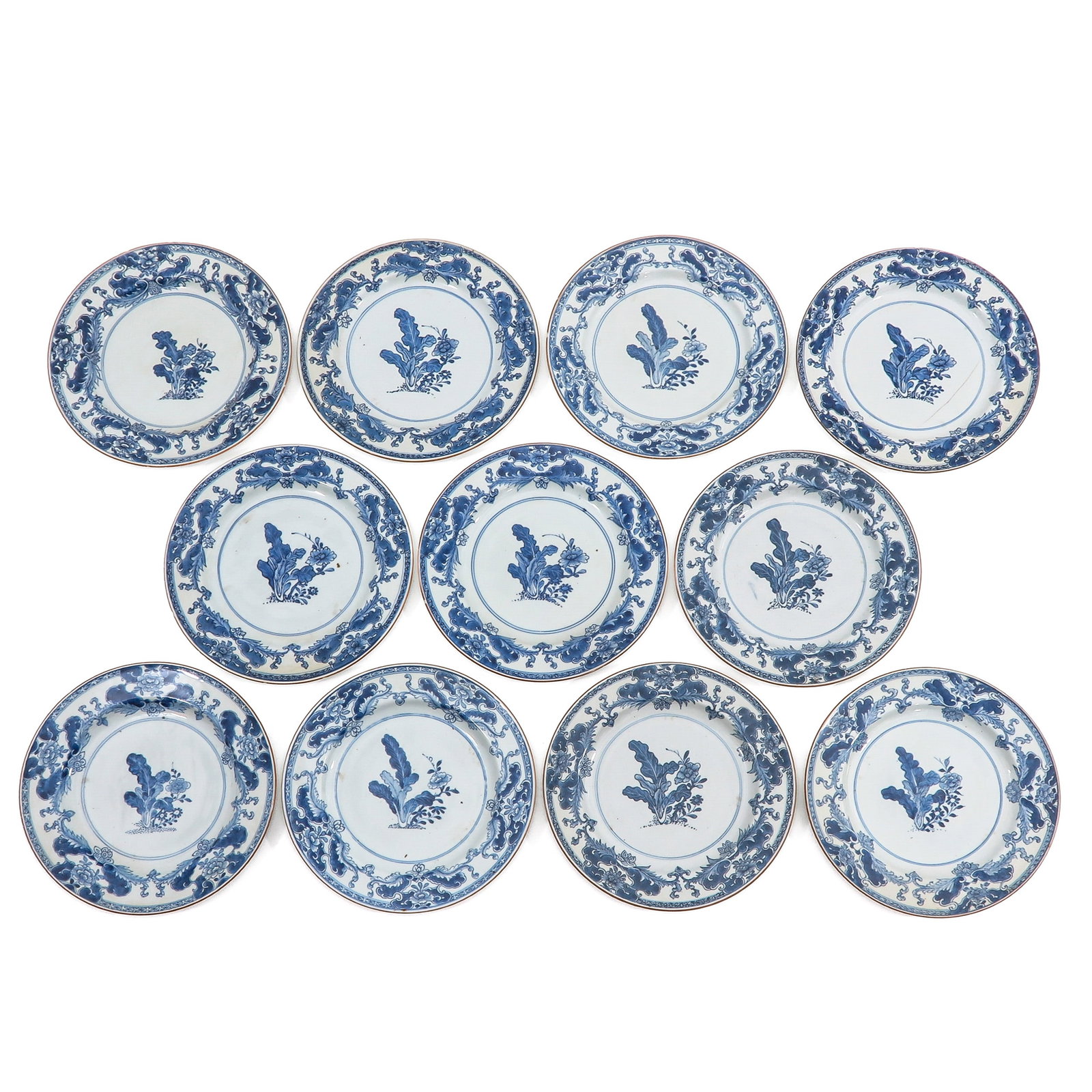 A Series of 11 Blue and White Plates: Each decorated with a floral spray within a scrolling foliate border, 27 cm. in diameter, 18th Century, in diverse conditions