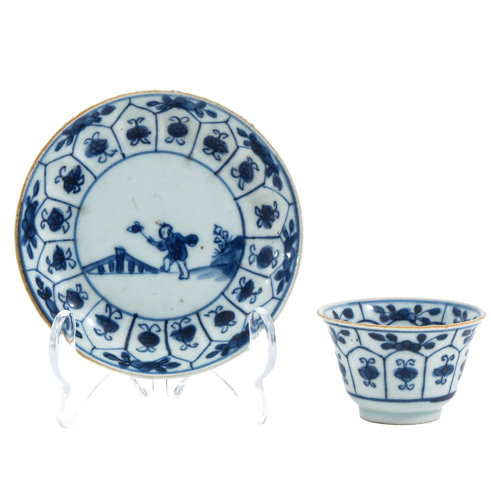 A Blue and White Cup and Saucer: Depicting a boy playing in a garden, 18th Century, saucer is 11 cm. in diameter,