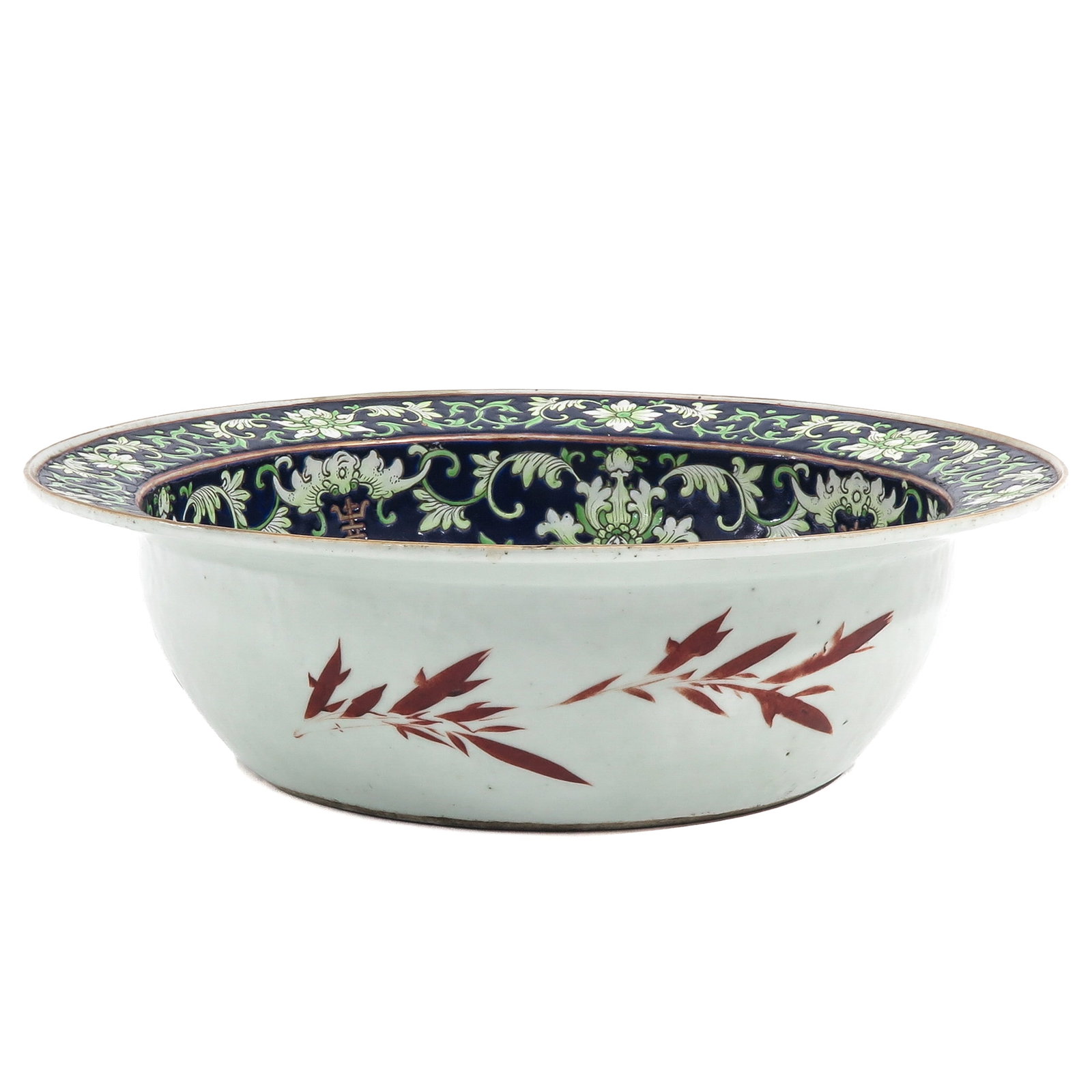 A Polychrome Decor Wash Basine: Decorated to the interior with scrolling floral motifs on a dark blue ground with the exterior in iron-red bamboo sprays, 37 cm. in diameter, chip.