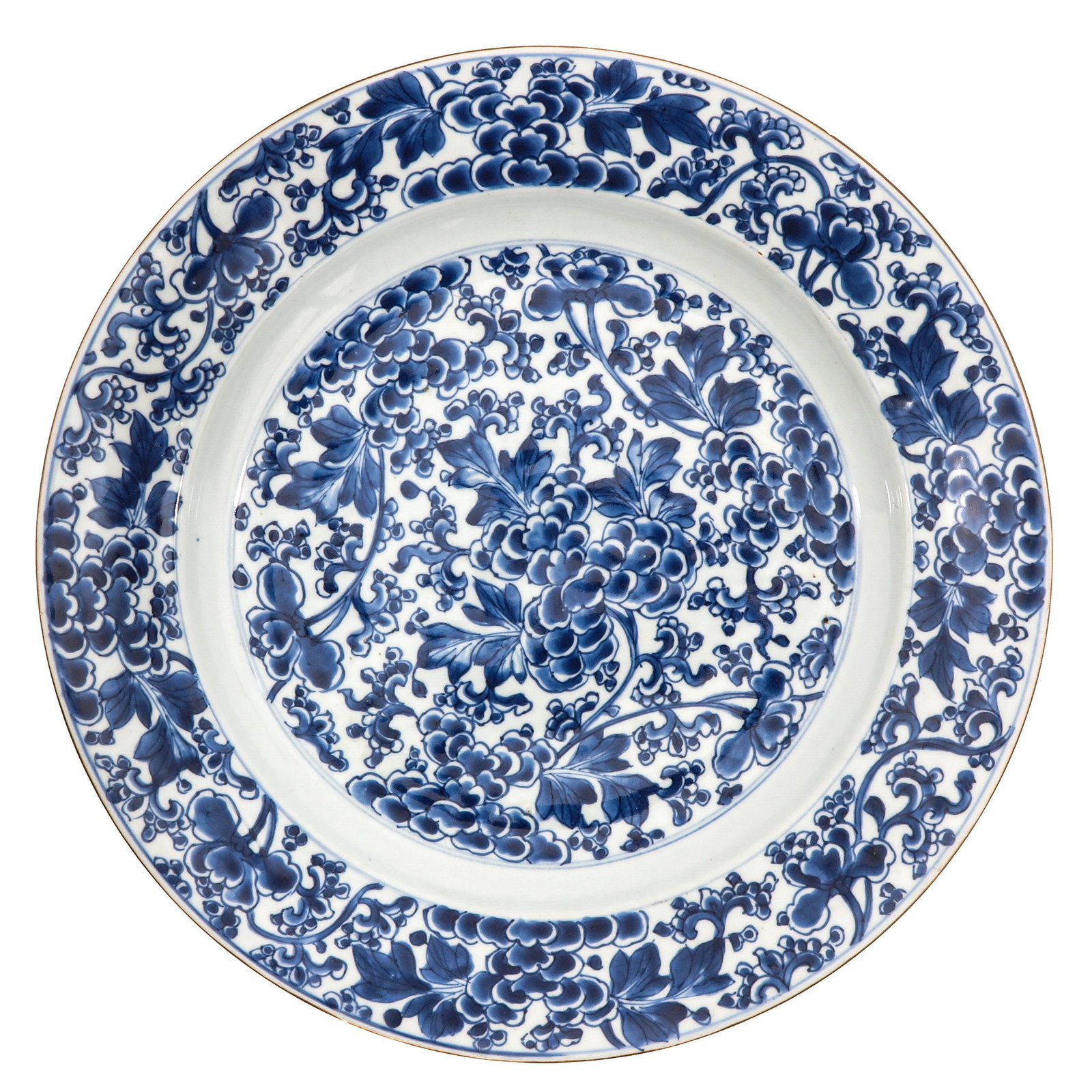A Blue and White Charger: Richly decorated with an all over design of flowering peonies and scrolling foliage, 18th Century, 36 cm. in diameter, chip.