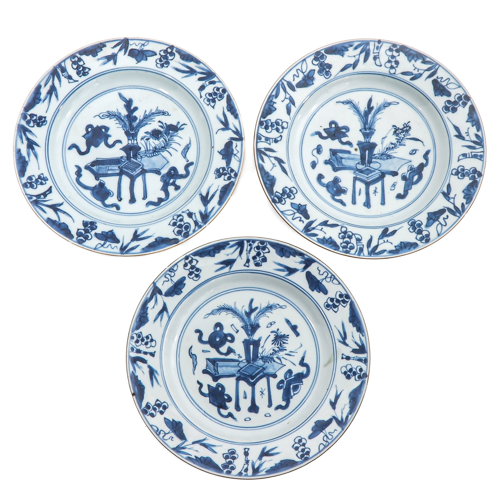 A Lot of 3 Blue and White Plates: Decorated with scholars objects and floral motifs within a bamboo and vine border, 18th Century, 23 cm. in diameter, chip and hairline.