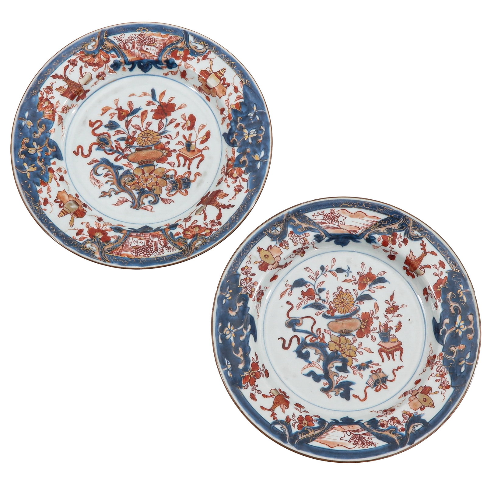A Pair of Imari Plates: Decorated with flowering urns, scholar?s objects and auspicious emblems in underglaze blue and iron red enamels, 18th Century, 23 cm. in diameter, chip.
