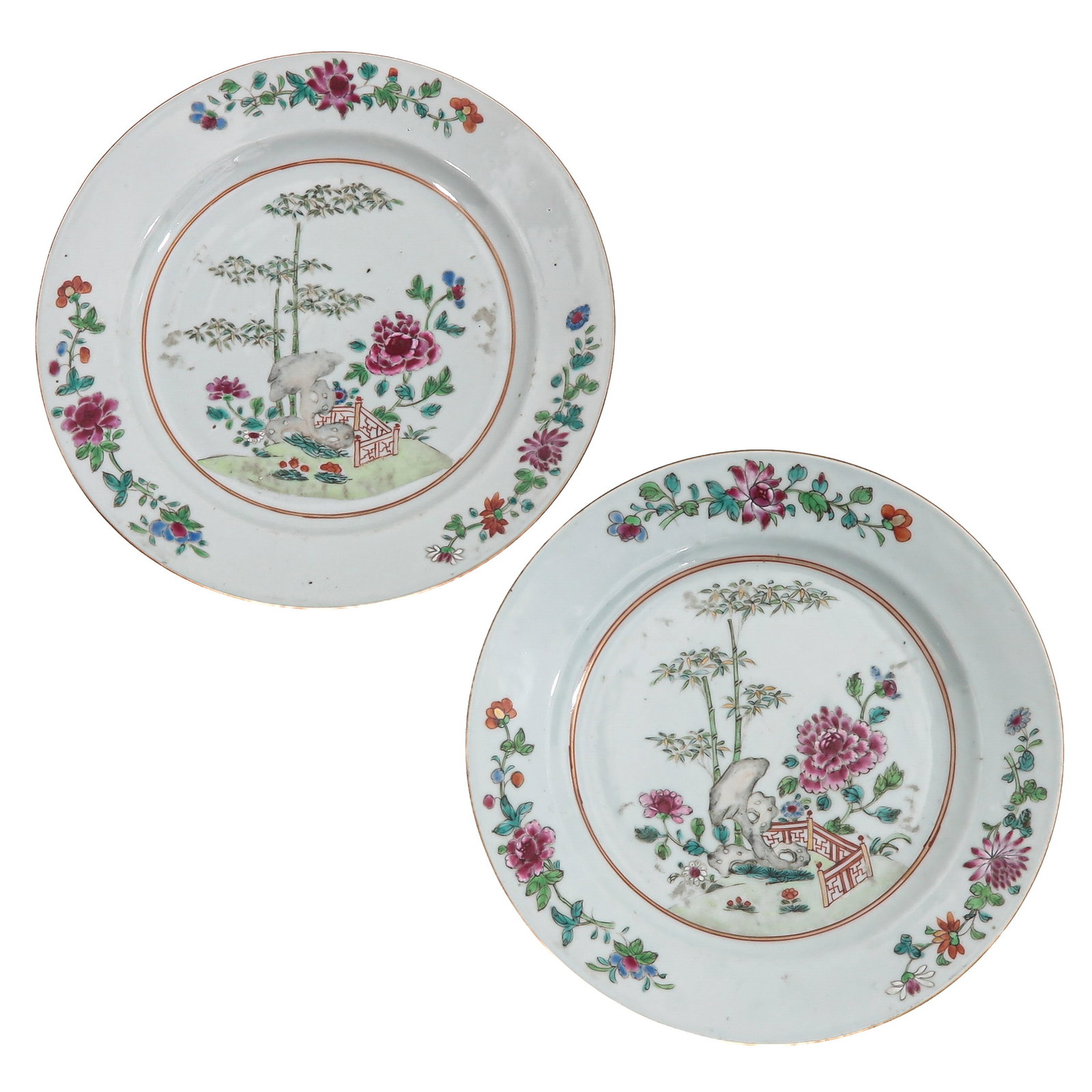 A Pair of Famille Rose Plates: Decorated with peonies, bamboo and rocks within a floral border, 18th Century, 23 cm. in diameter.