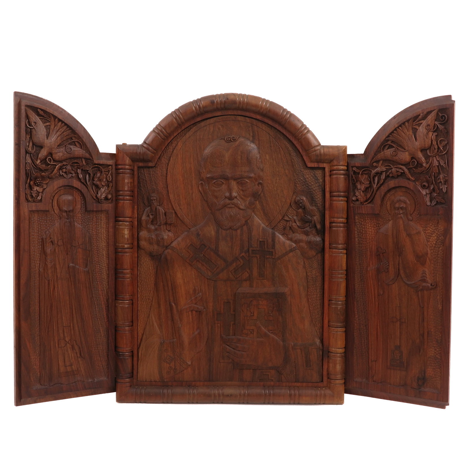 A Carved Wood Triptych: carved wood, centrally a bishop saint with halo, flanked by two standing saints, richly carved with birds, floral ornaments and religious representations, dimensions closed: 53 x 72 cm. Signed Metap