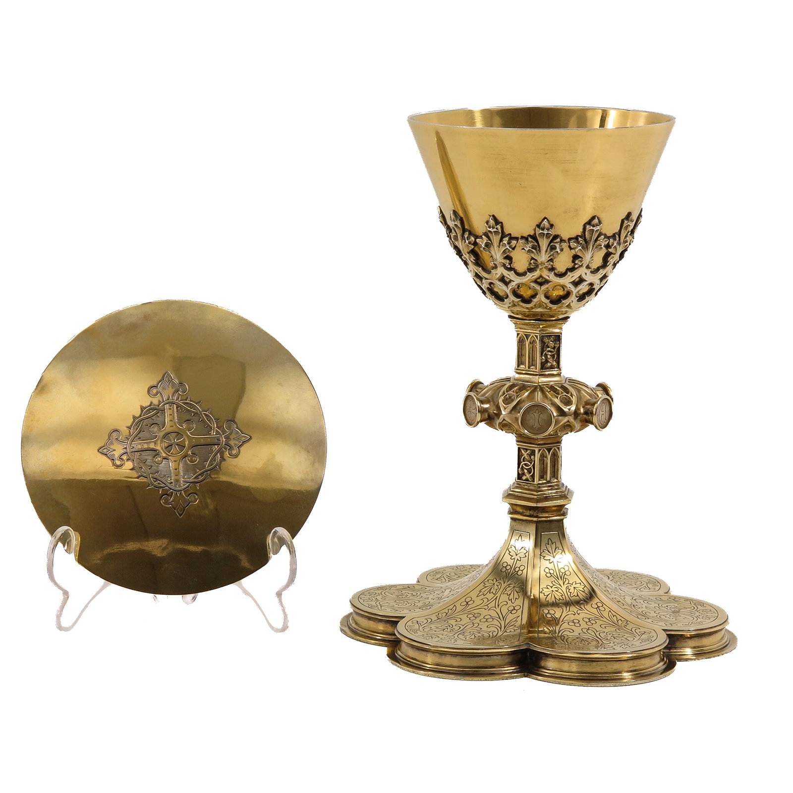 A Chalice: with paten, Neo-Gothic, richly gilt, with foot of engraved floral decoration, cross-shaped node with medallions, openwork foliage on the cuppa and an engraved cross on the paten, height 22 cm.