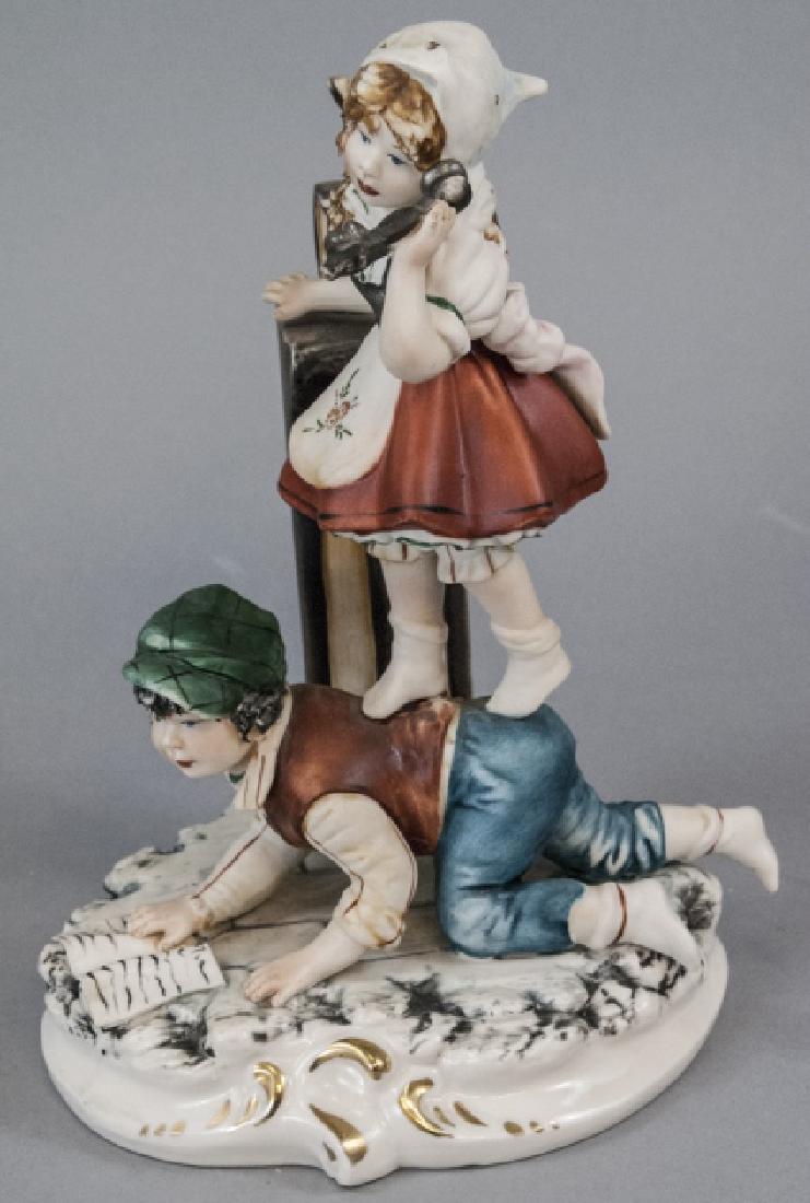 Capodimonte Meneghetti Bisque Porcelain Figurine: Capodimonte Meneghetti Bisque Porcelain Figurine. This bisque porcelain figurine by Capodimonte features a boy and a girl reading and talking on the telephone. Capodimonte mark can be seen on the back